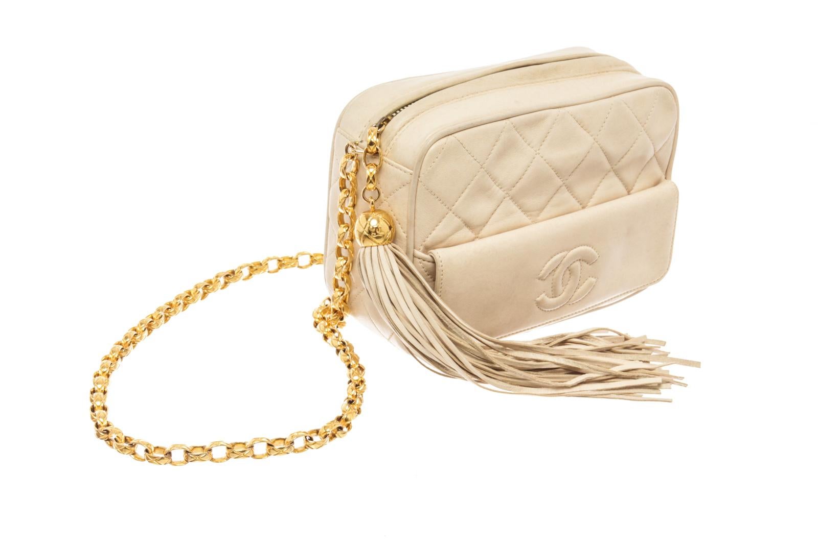Chanel Cream Lambskin Tassel Camera Shoulder Bag with Neutrals Lambskin, Front flap pocket with Interlocking CC Logo & Quilted Pattern, Gold-Tone Hardware, Interior leather with one zip pocket, gold chain Single Shoulder Strap, Tassel Accents,