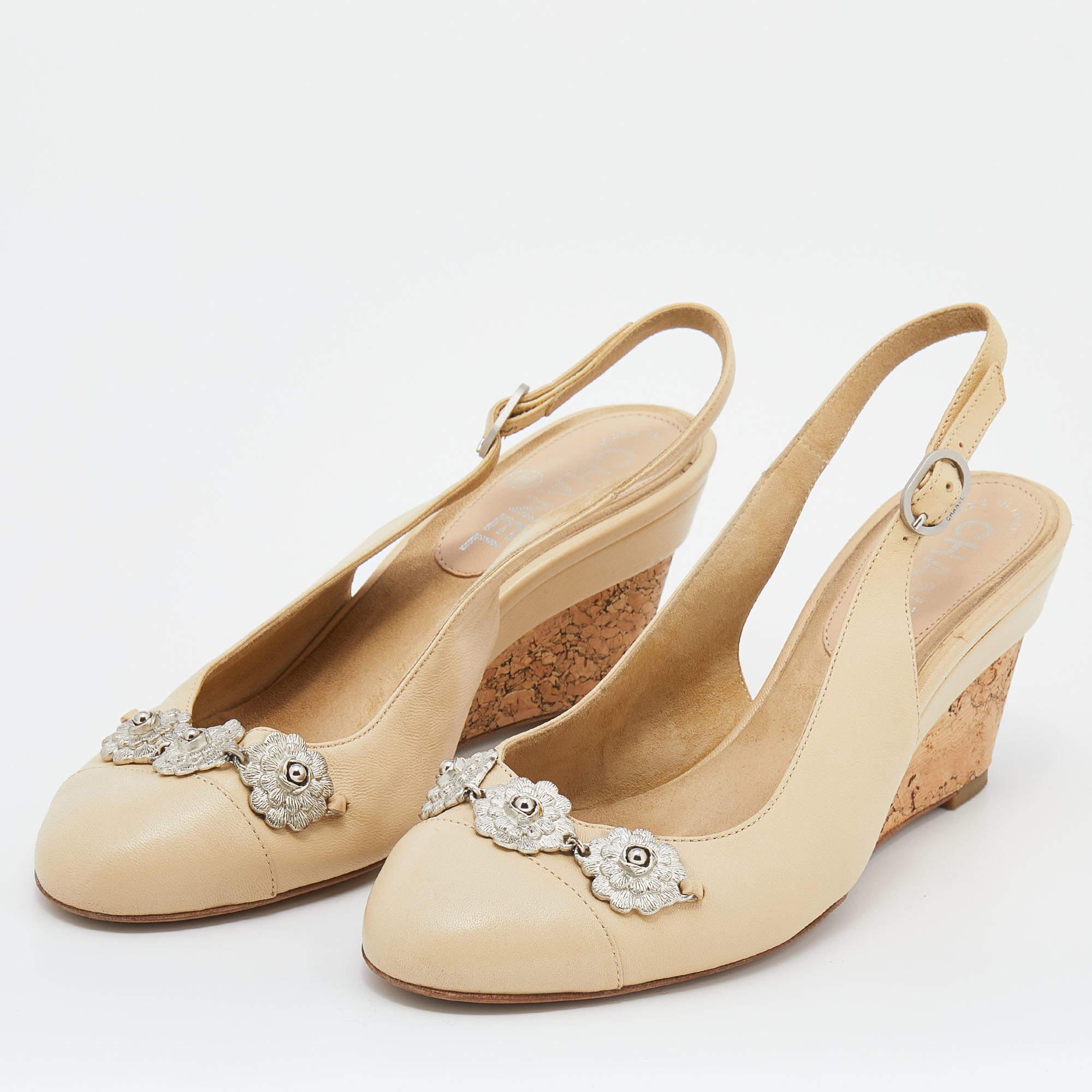 Cette paire de sandales intemporelles de Chanel est encore plus belle aux pieds. Ces chaussures élégantes en cuir crème sont dotées de bouts ronds ornés de fleurs, de talons compensés et d'escarpins à boucle pour une finition élégante.

