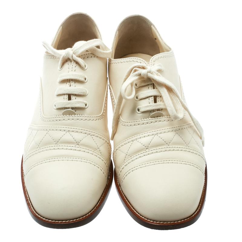 Make an impressive style statement in these oxfords from Chanel! The cream oxfords are crafted from leather and feature round toes. They have been styled with the signature quilted stitch pattern and lace-ups on the vamps and a contrasting CC logo