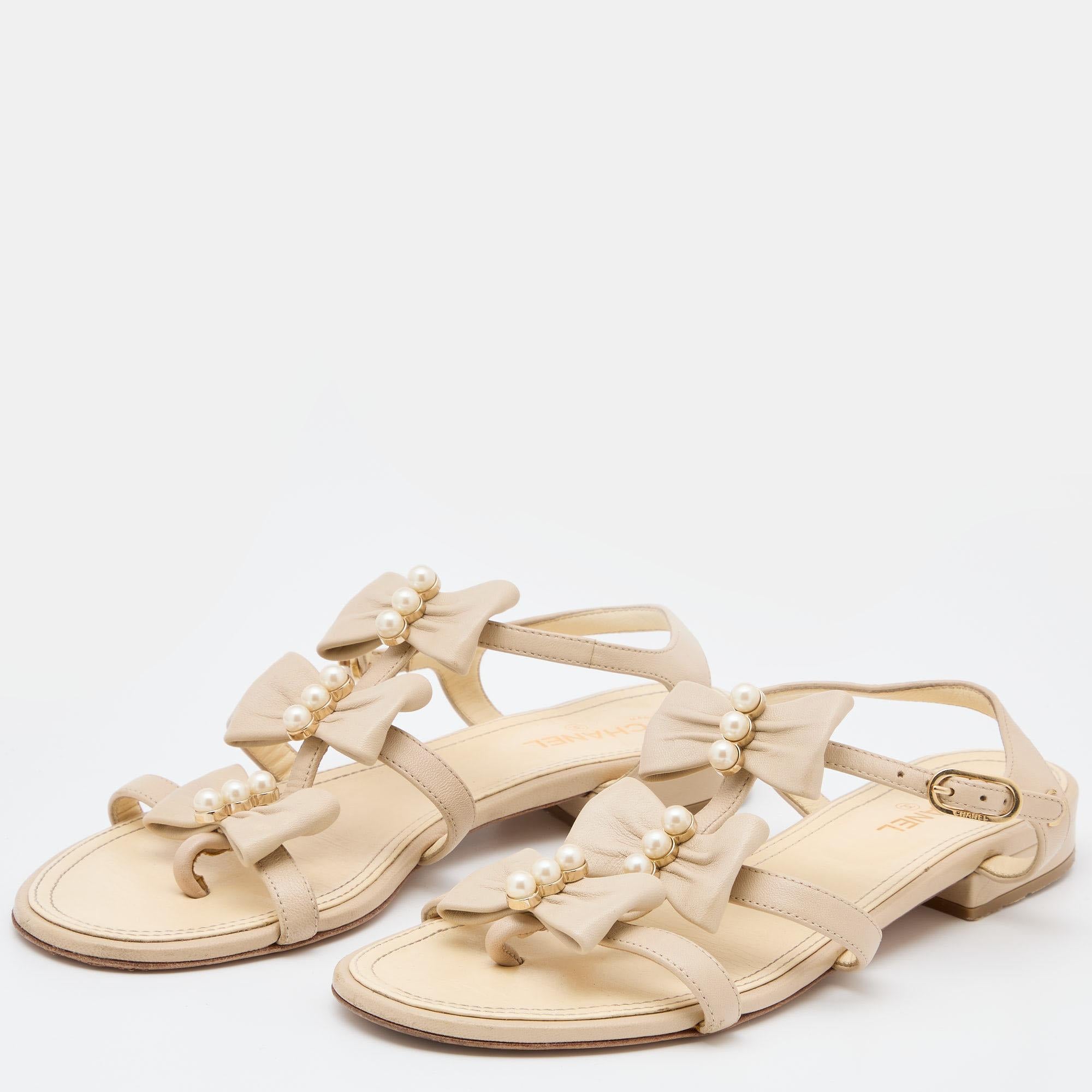 These Chanel sandals are crafted from quality leather for your comfort. Flaunt this fabulous cream pair as you step out in style. It features a strappy design with pearl-embellished bow details. The sandals are complete with buckled ankle straps and