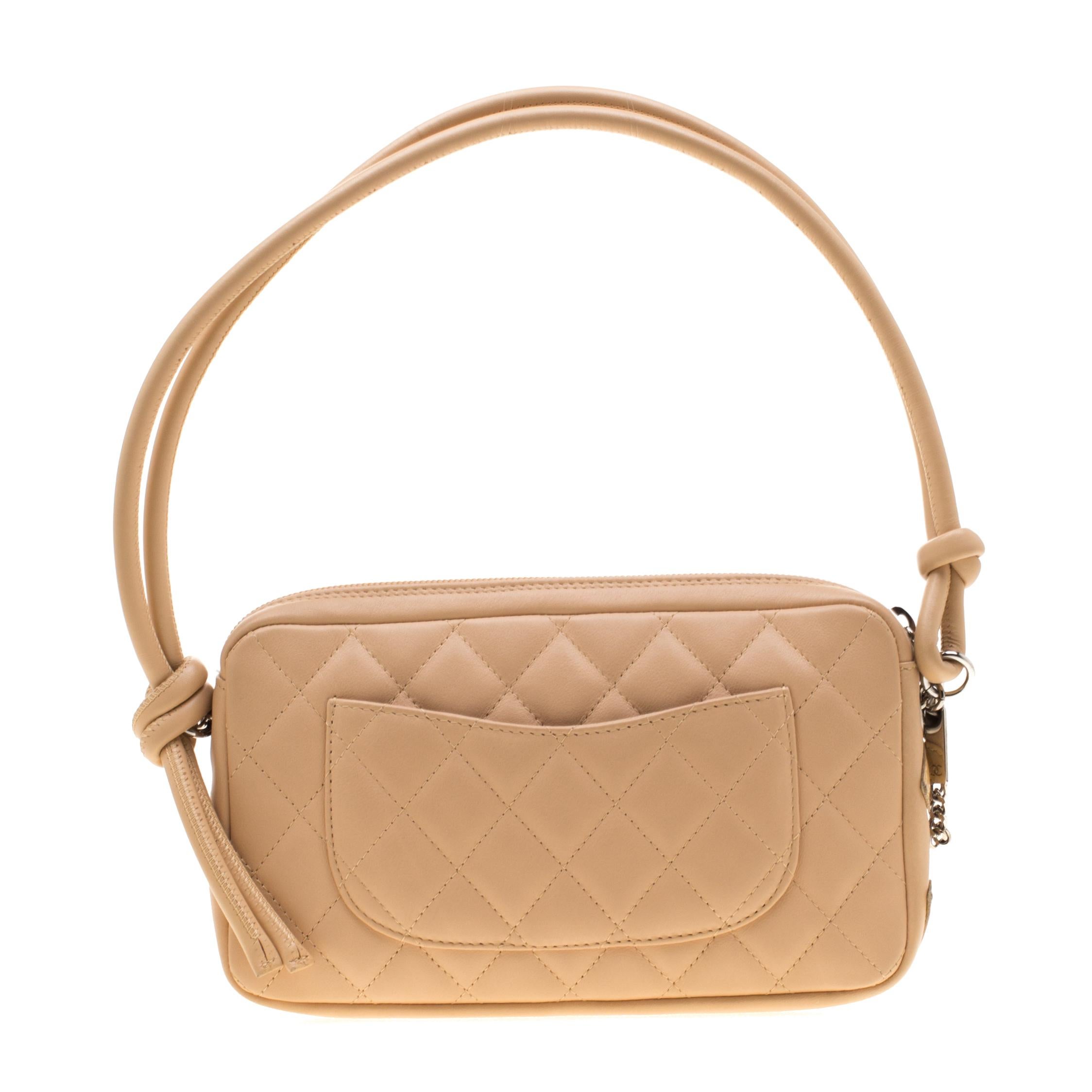 Easy to swing and casually stylish, this gorgeous Chanel Ligne Cambon Pochette is a highly appealing bag. Crafted in cream quilted leather with the CC symbol in a slightly darker shade, this top handle bag opens with a silver-tone zipper at the top