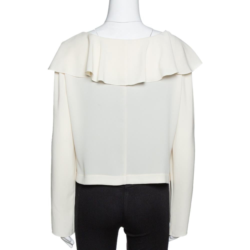 This Chanel blouse is carefully crafted for a relaxing yet modish formal look. Made from quality fabrics, it features a subtle cream shade along with a ruffled neckline and long sleeves. This blouse will lend an urban feel remaining true to the