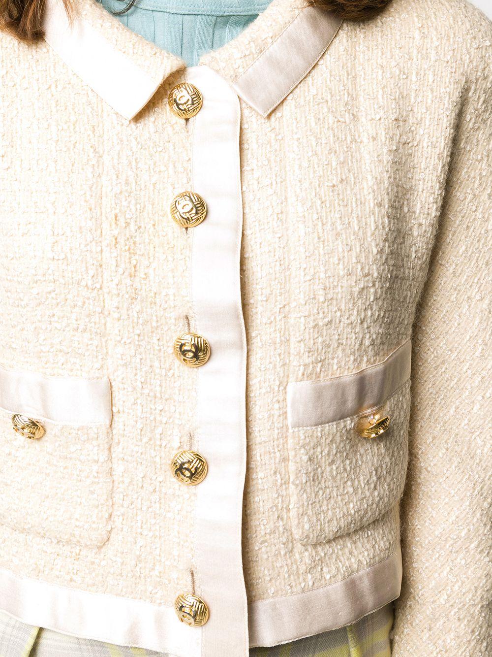 Meticulously crafted in France from a contrasting two-tone palette of cream and ivory tweed, this sophisticated pre-loved skirt suit by Chanel gives a modern update to the brand's signature knit. The jacket features a classic collar, a