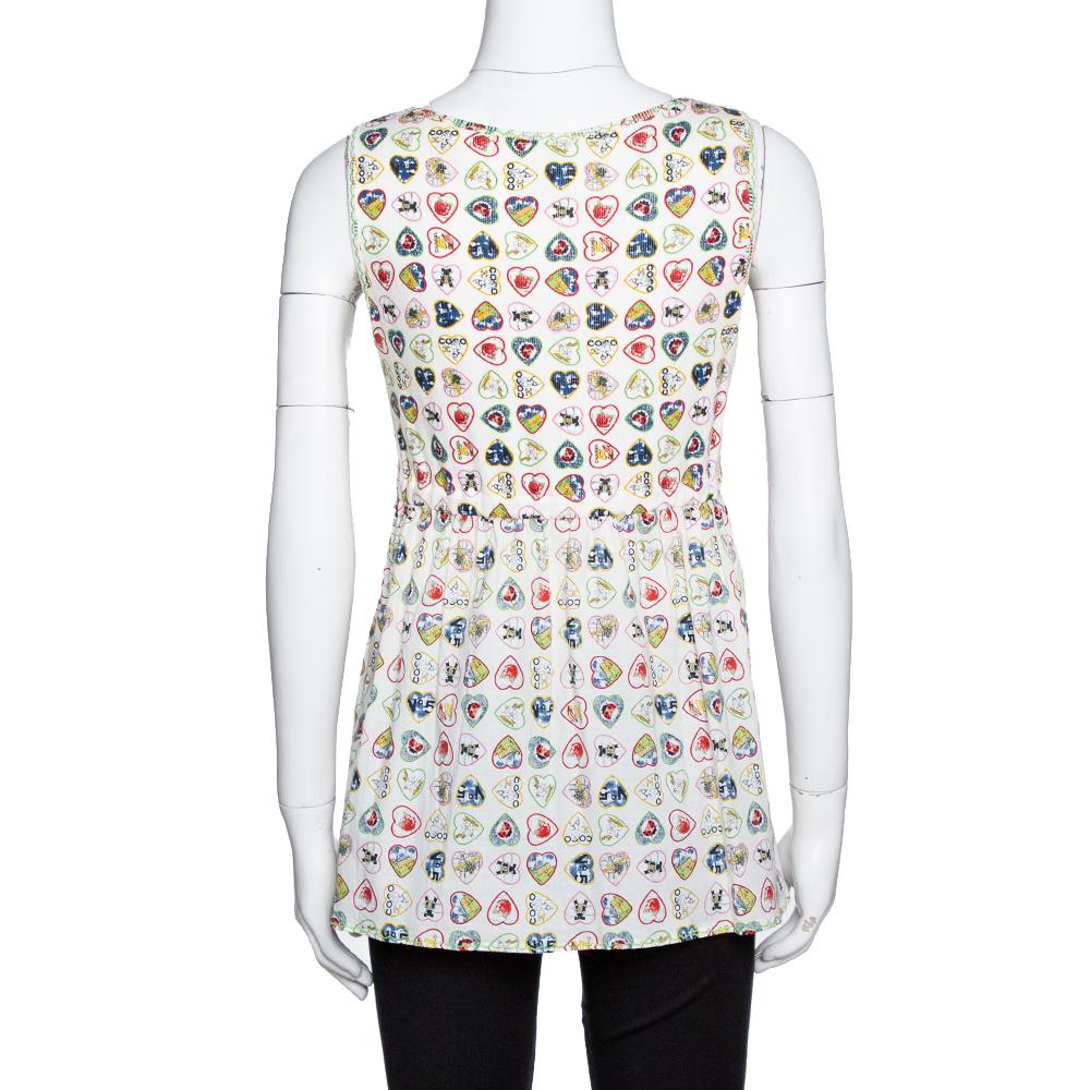 How lovely does this Chanel top look! The cream sleeveless creation is made of a cotton blend and features a valentine inspired print all over. It has been styled with a plunging V-neckline and a tie-up at the waist. Pair it with dark-hued pants and