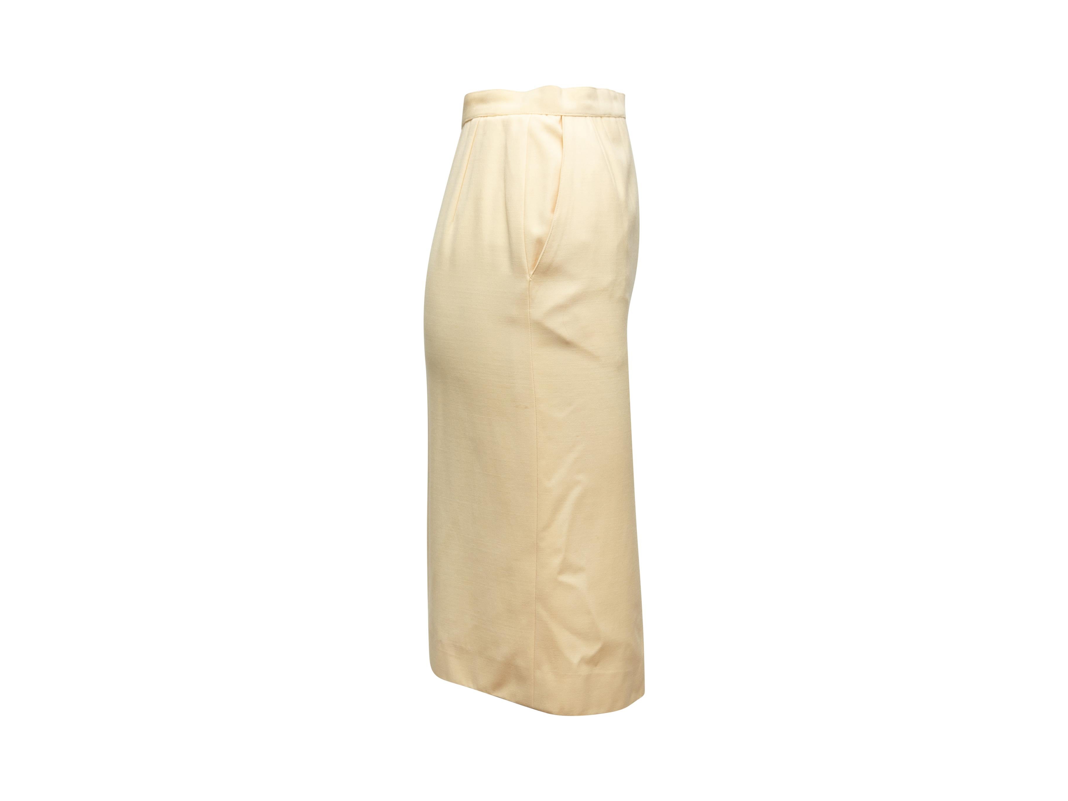 Product details: Cream wool knee-length pencil skirt by Chanel. Vent at front center hem. Dual hip pockets. Zip and CC button closure at side. 24