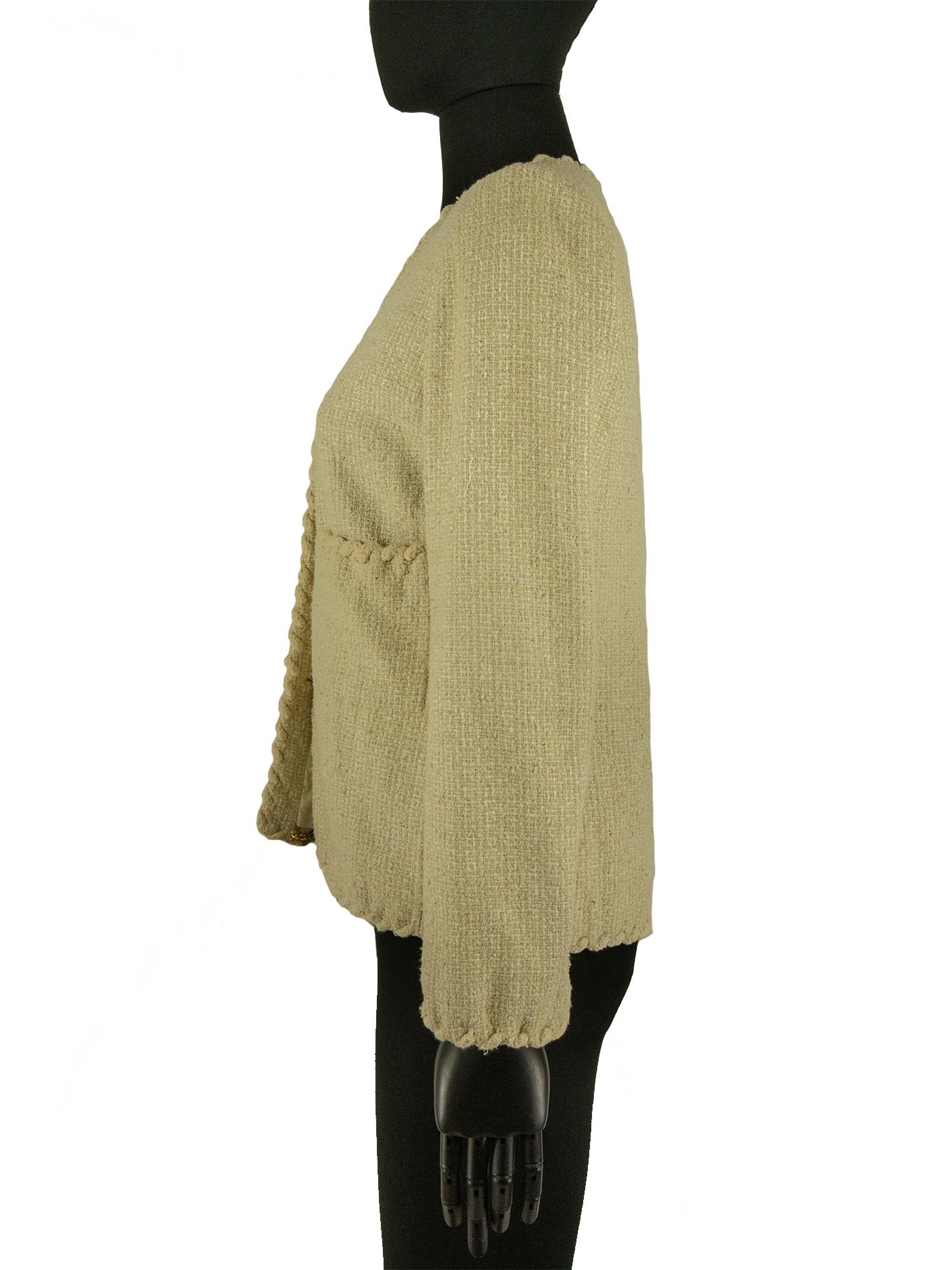 A 1970s Chanel jacket in cream tweed, with a rope inspired detail along the collar, hems, cuffs and pockets. The centre front is fastened with three buttons with gilt lion details. The bodice holds 4 pockets, two patches and two hidden, and the hem