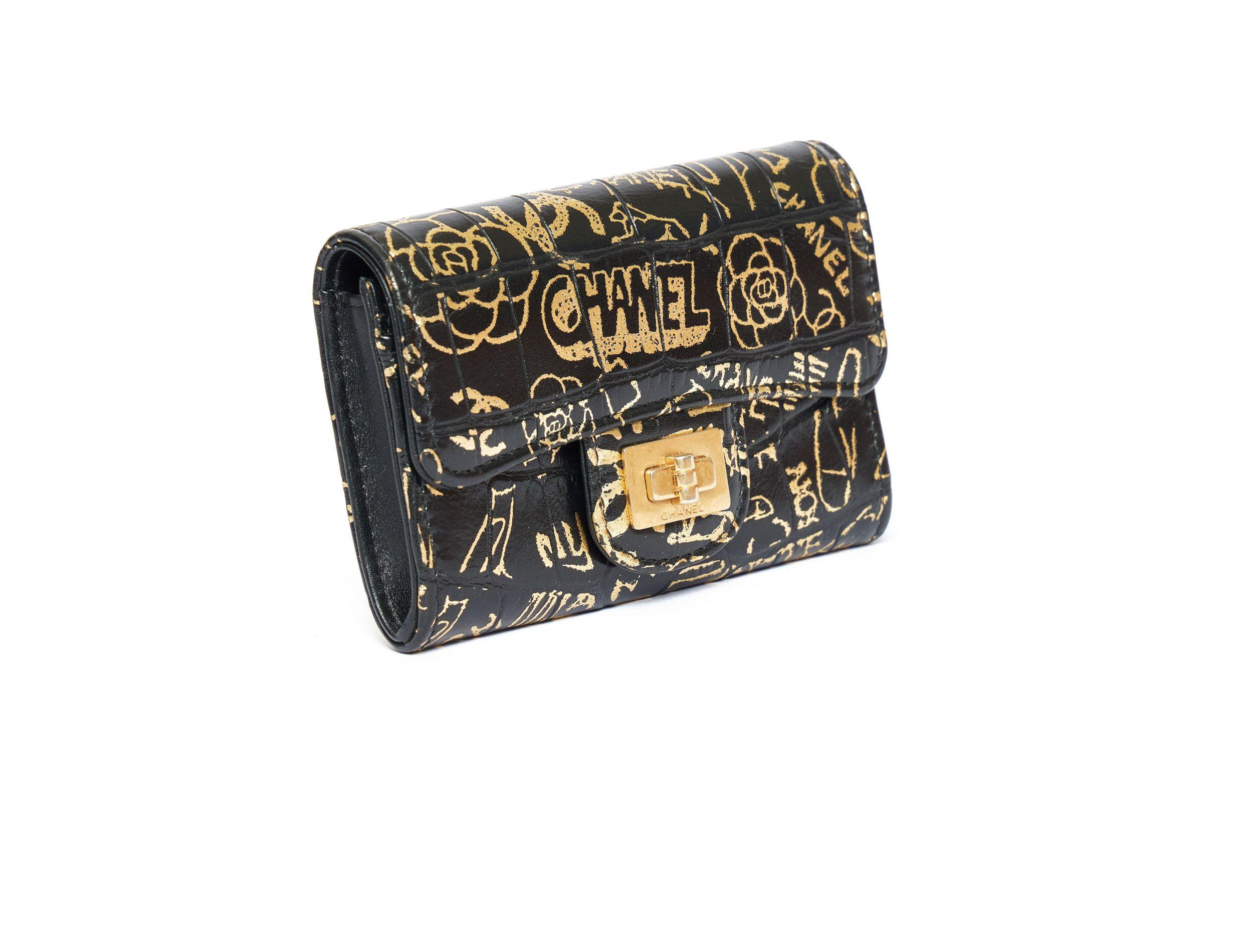 Chanel Limited Edition credit card case in black lambskin leather which looks like crocodile. The case is painted with a graffiti which shows flowers and Chanel written on it in different ways. The snap looks like a small turn lock with Chanel