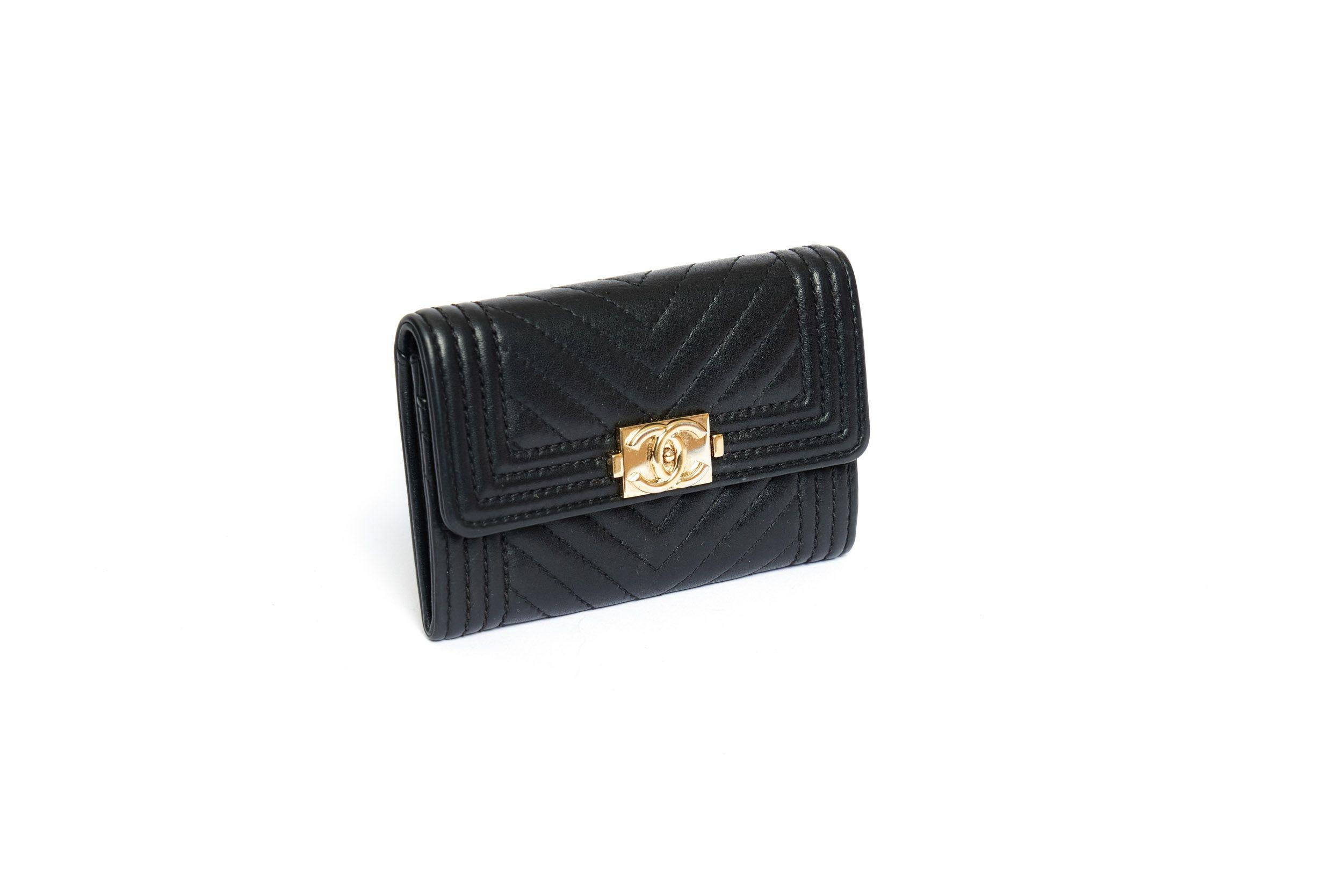 Chanel credit card case in black quilted lambkin leather. It is in beautiful condition and has only small wear marks. The case closes with a snap which has a CC logo. The interior is made of black fabric and has two compartments. The time stamp