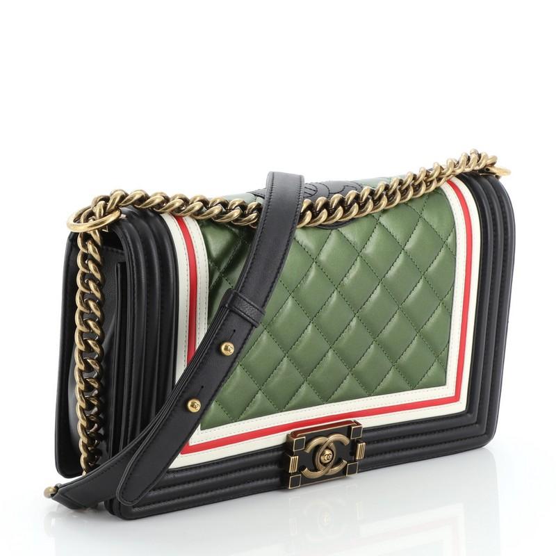 This Chanel Crest Boy Flap Bag Quilted Lambskin New Medium, crafted from black, red, and green multicolored quilted lambskin leather, features a chunky chain link strap with leather shoulder pad, red and white border trims and aged gold-tone