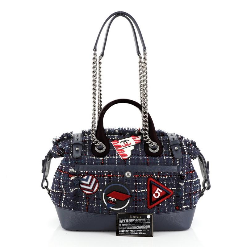 This Chanel Crest Trip Bowling Bag Patch Embellished Tweed and Grained Calfskin Medium, crafted in blue multicolor tweed calfskin leather trims, features Chanel printed airport motif patches, dual-rolled leather handles, protective based studs,