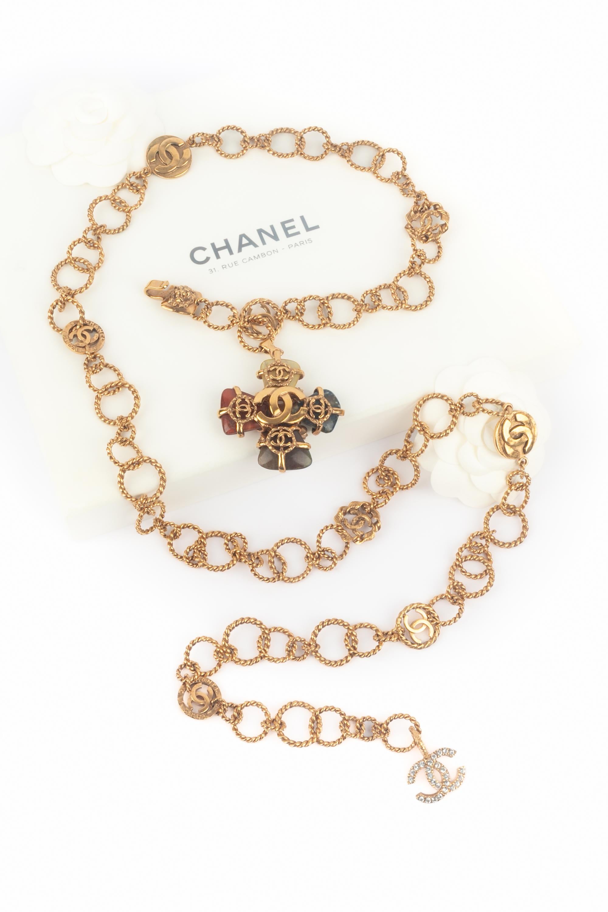 CHANEL - (Fabriqué en France) Ceinture bijou en métal doré avec une breloque croix en strass et pierres dures. Collectional automne-hiver 2005 sous la direction artistique de Karl Lagerfeld.

Condit :
Très bon état.

Dimensions :
Longueur : 120