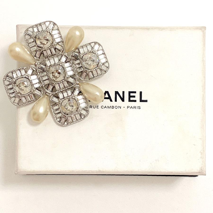 Superb brooch CHANEL House cross-shaped, set with Swarovski rhinestones chopsticks and squares. 4 drop-shaped beads are at the 4 ends.
It comes from the spring-summer 2009 collection. Made in France.
This jewel is in very good condition. A pearl has