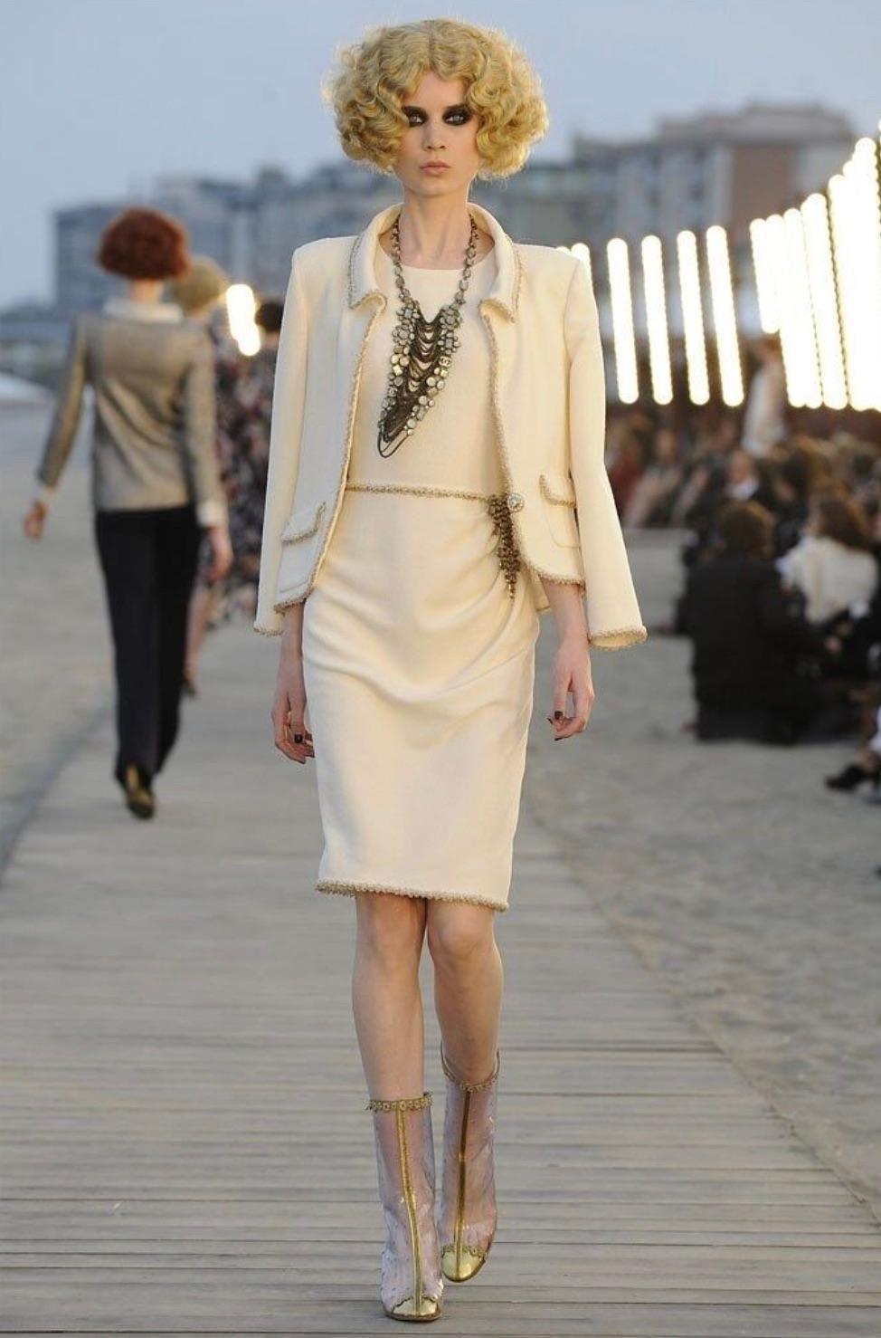 Enjoy timeless elegance with this single-breasted jacket from Chanel's Cruise 2010 collection. Crafted in luxurious ivory tweed, its tailored silhouette with a notched lapel collar showcases impeccable craftsmanship. Adorned with the signature gold