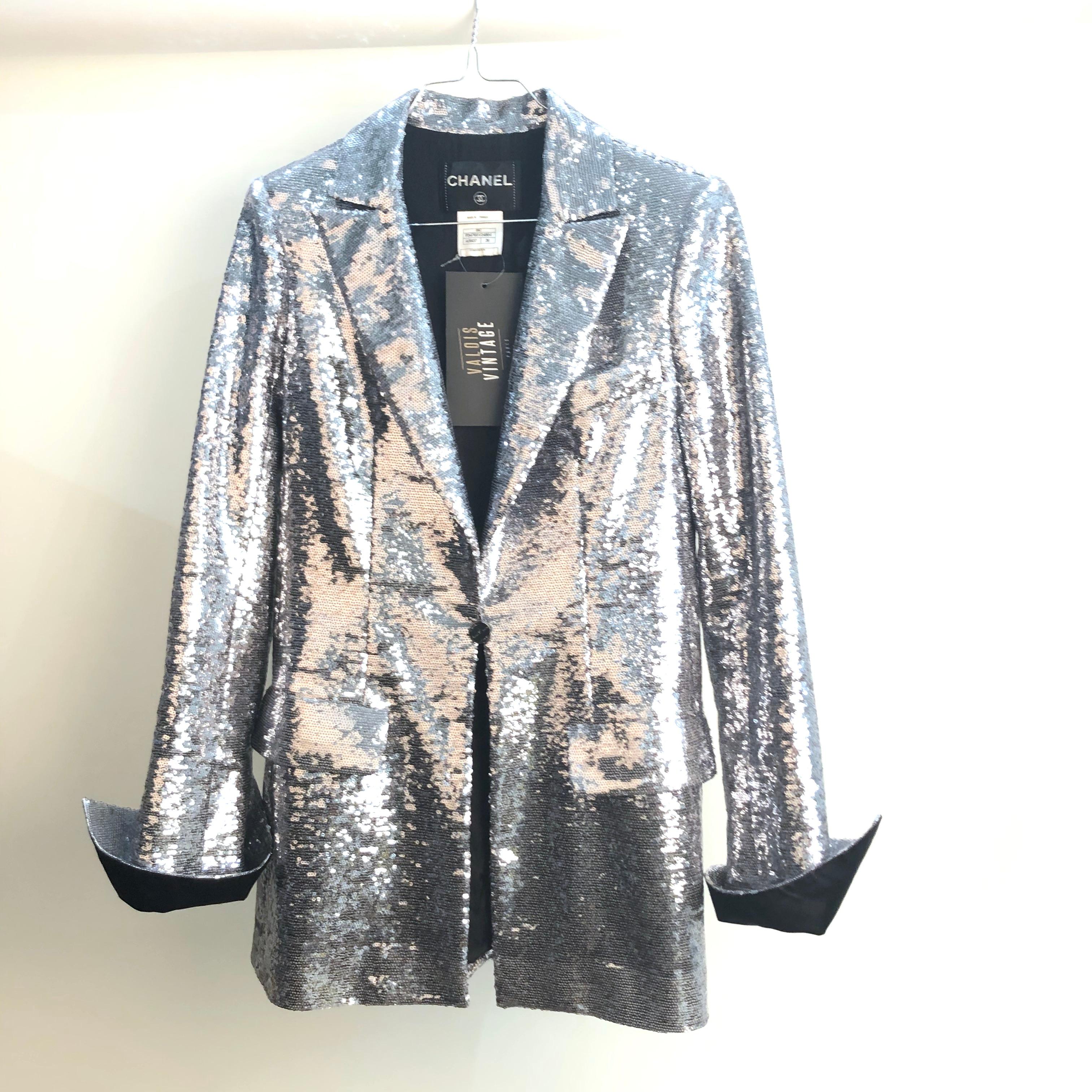 Very beautiful CHANEL piece from the Paris-Miami Cruise Collection in 2009. Blazer entirely embroidered with silver sequins, lined with black silk camellia monogram. With two flat pockets and a slit pocket on the chest, it closes with a single