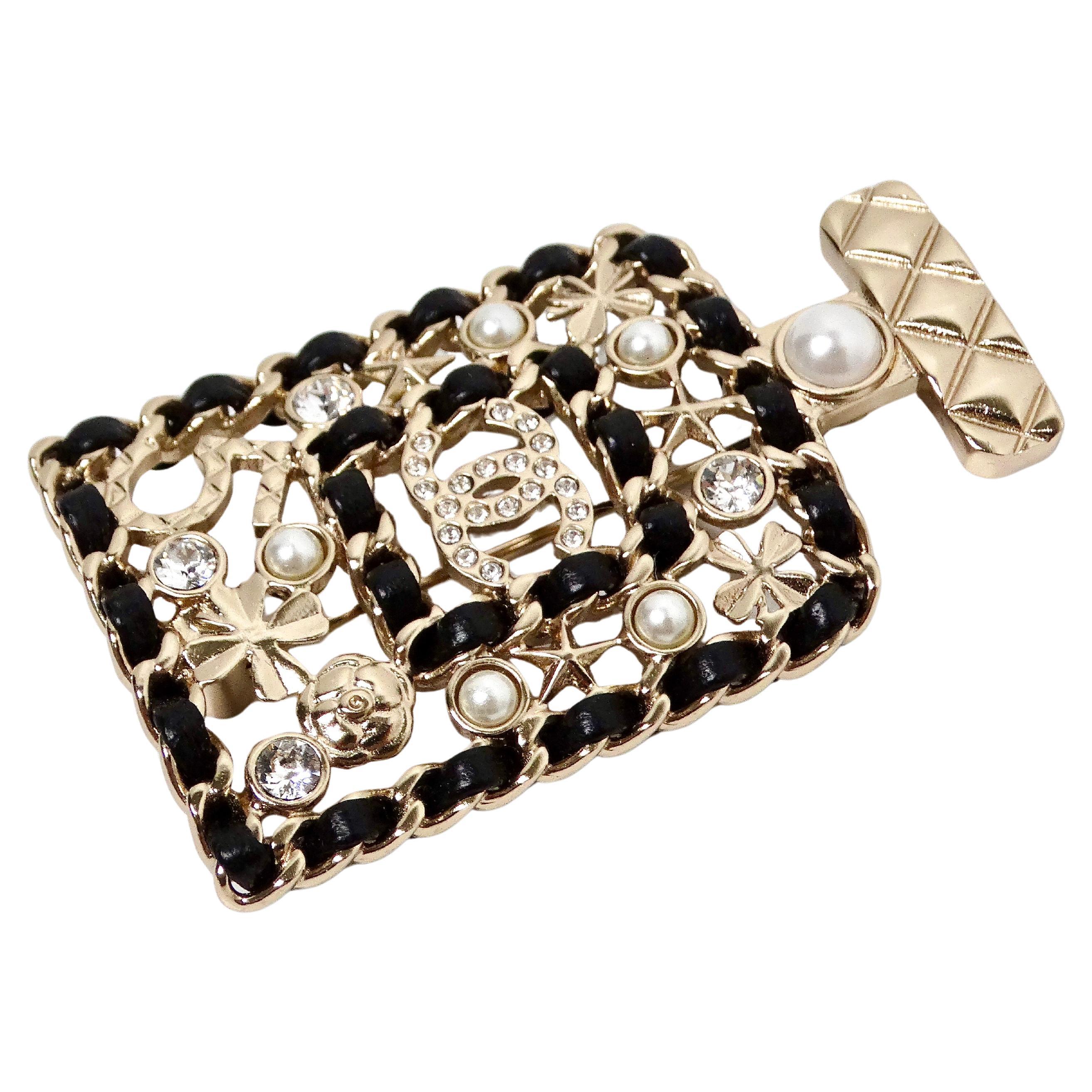 El broche Chanel de cristal y cuero negro estilo frasco de perfume nº 5 2020 es un accesorio impresionante y sofisticado que combina a la perfección el encanto vintage con la elegancia moderna. Elaborado con meticulosa atención al detalle, este