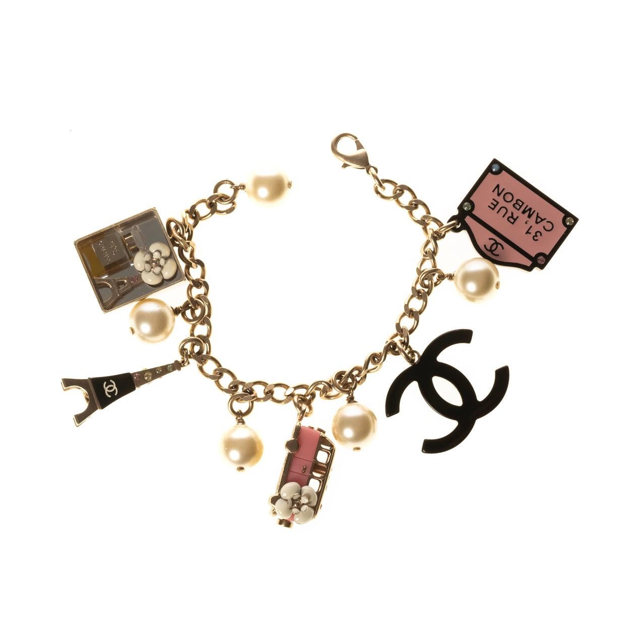 Chanel bracelet with multiple charms including an Eiffel Tower, vintage bus, Chanel logo and multiple faux pearls. Featuring a weight of roughly 50g, Chanel signature, Strass crystal embellishments, resin and enamel accents and lobster clasp