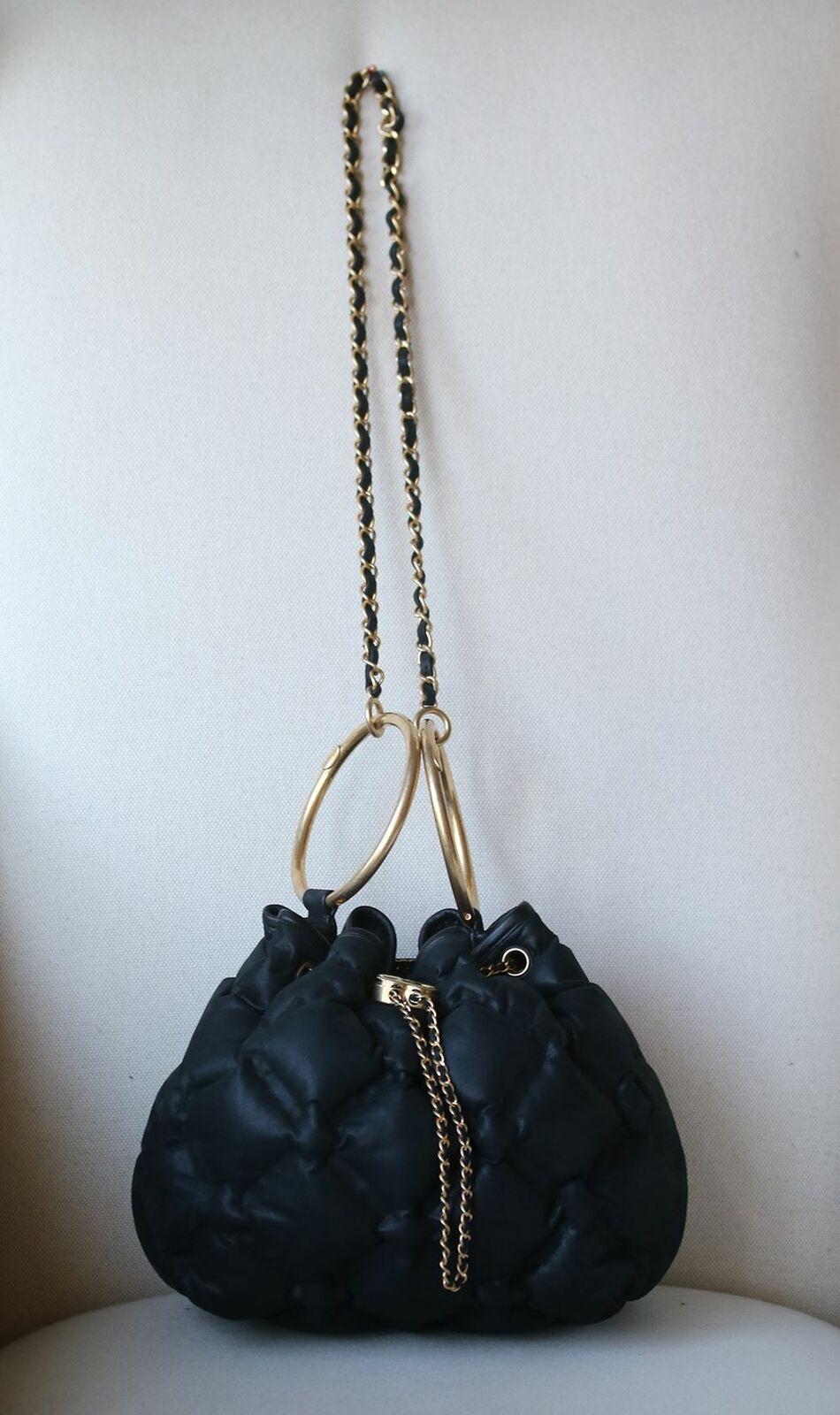 Chanel Lambskin CC Chain Drawstring Bag in black. The bag features a leather threaded shoulder strap with matte gold hardware with a leather shoulder pad. This beautiful bag is detailed with a leather threaded chain cinch cord along the top frame