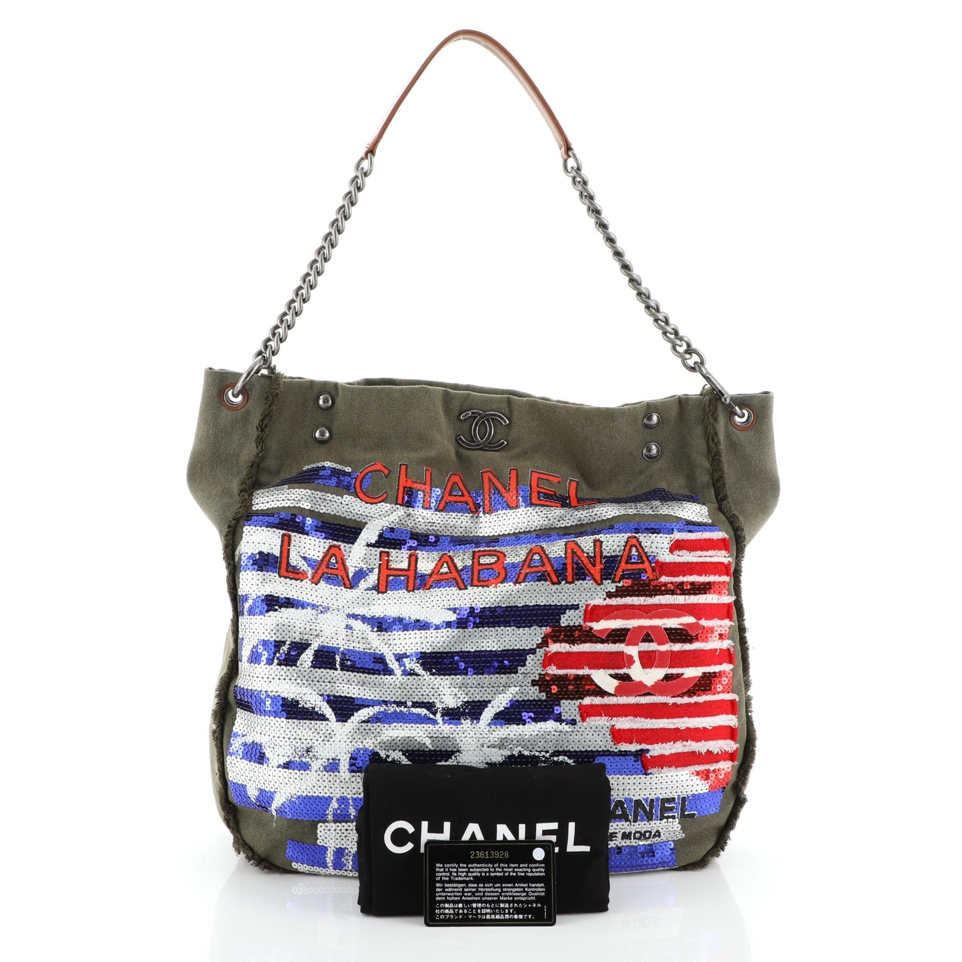 This Chanel Cuba La Habana Chain Hobo Sequin Embellished Canvas Large, crafted from green sequin embellished canvas, features CC logo at front, chain link shoulder strap, and aged silver-tone hardware. Its magnetic snap button closure opens to a