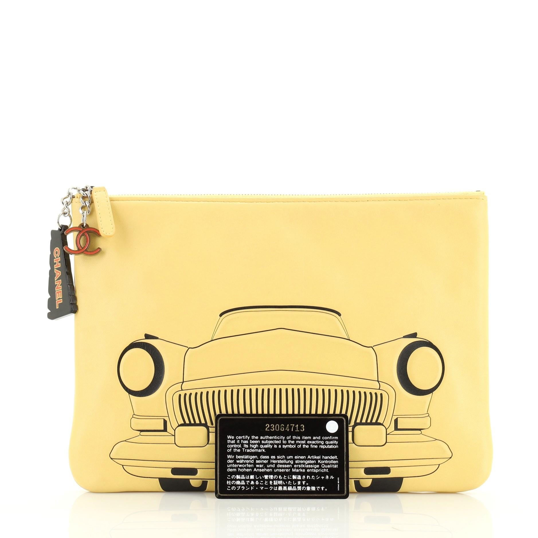 This Chanel Cuba La Habana O Case Clutch Printed Embossed Lambskin Medium, crafted from yellow printed embossed lambskin leather, features a car motif print, CC charm zip pull and silver-tone hardware. Its zip closure opens to a yellow nylon