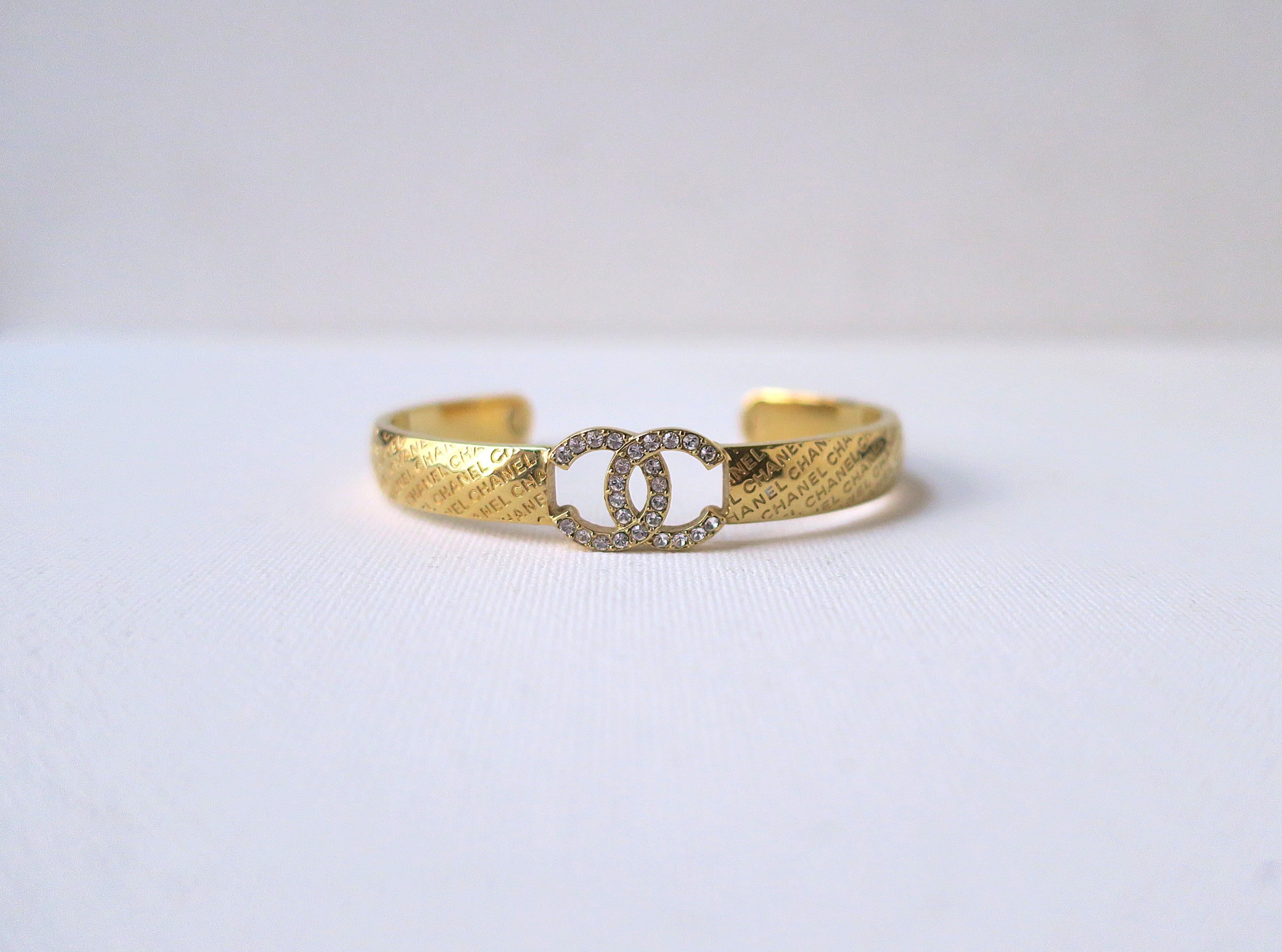Magnifique bracelet manchette Chanel en métal doré avec l'inscription 