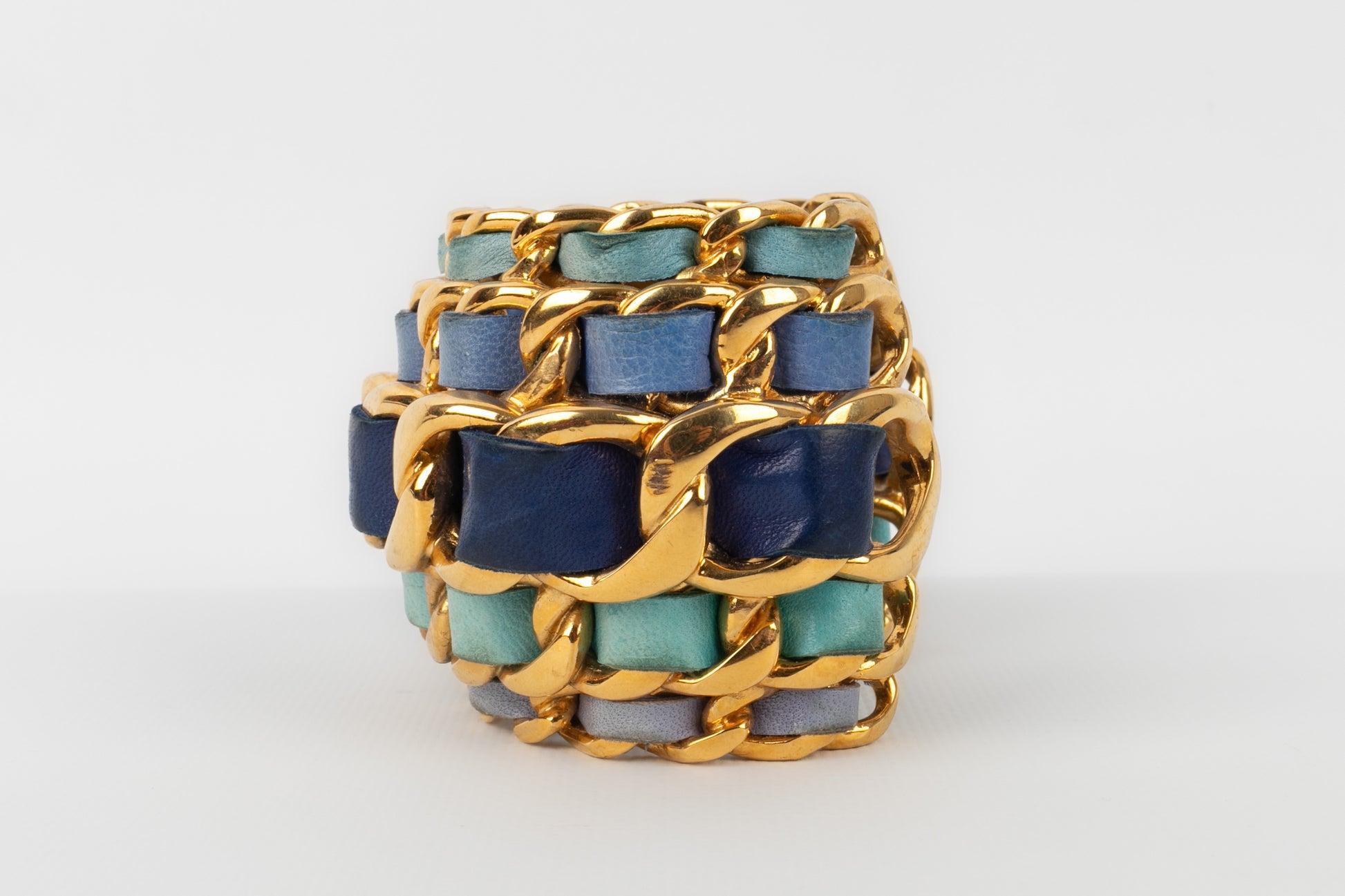 Chanel - (Made in France) Golden metal cuff bracelet interlaced with blue tone leather. 2cc6 Collection - 1991 Fall-Winter.

Additional information:
Condition: Good condition
Dimensions: Wrist circumference: 16 cm - Opening: 3 cm - Height: 6