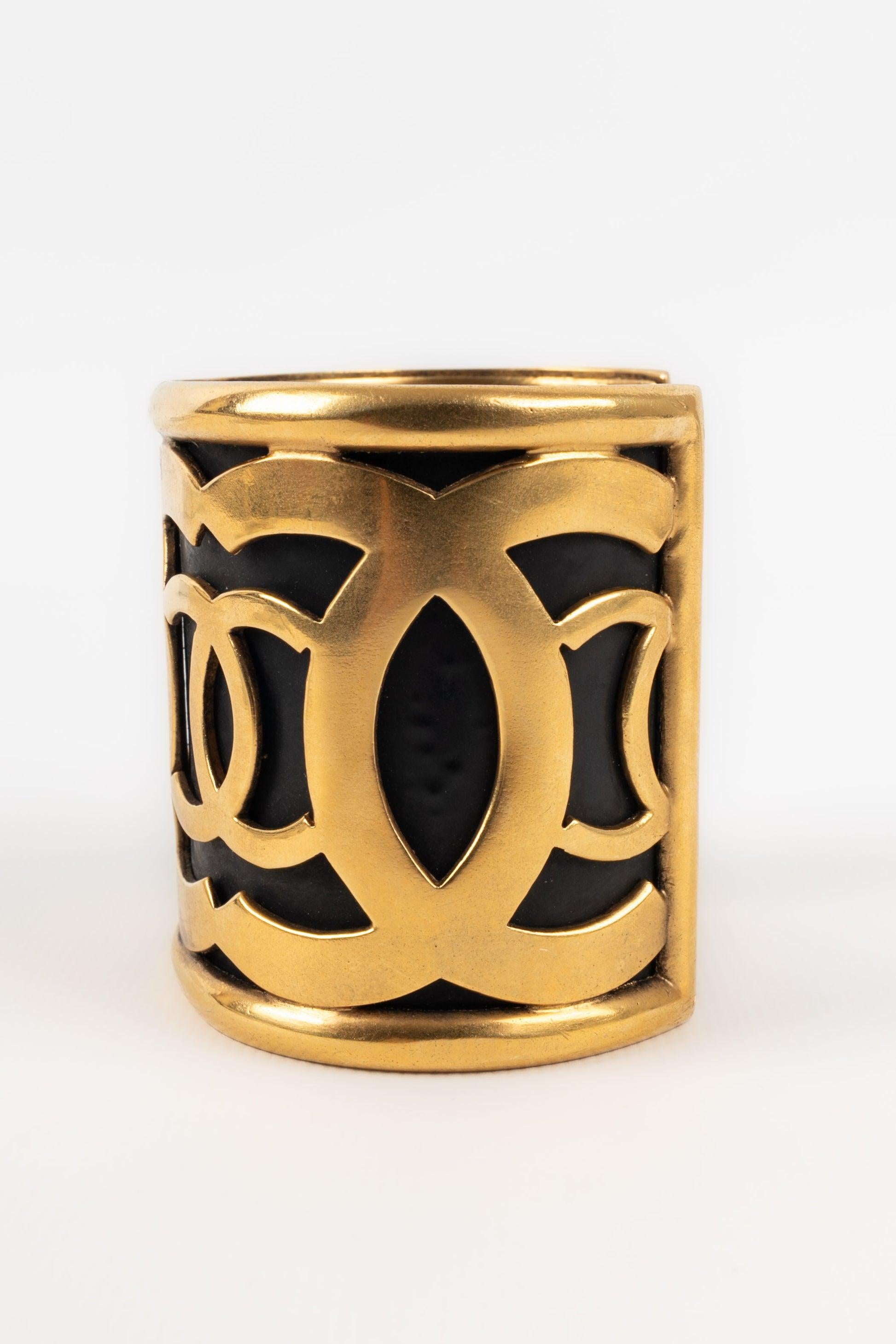 Chanel - Manschettenarmband aus goldenem Metall auf schwarzem Grund.

Zusätzliche Informationen:
Zustand: Sehr guter Zustand
Abmessungen: Höhe: 6 cm - Länge: 14,5 cm - Öffnung: 3,5 cm

Sellers Referenz: BRAB141