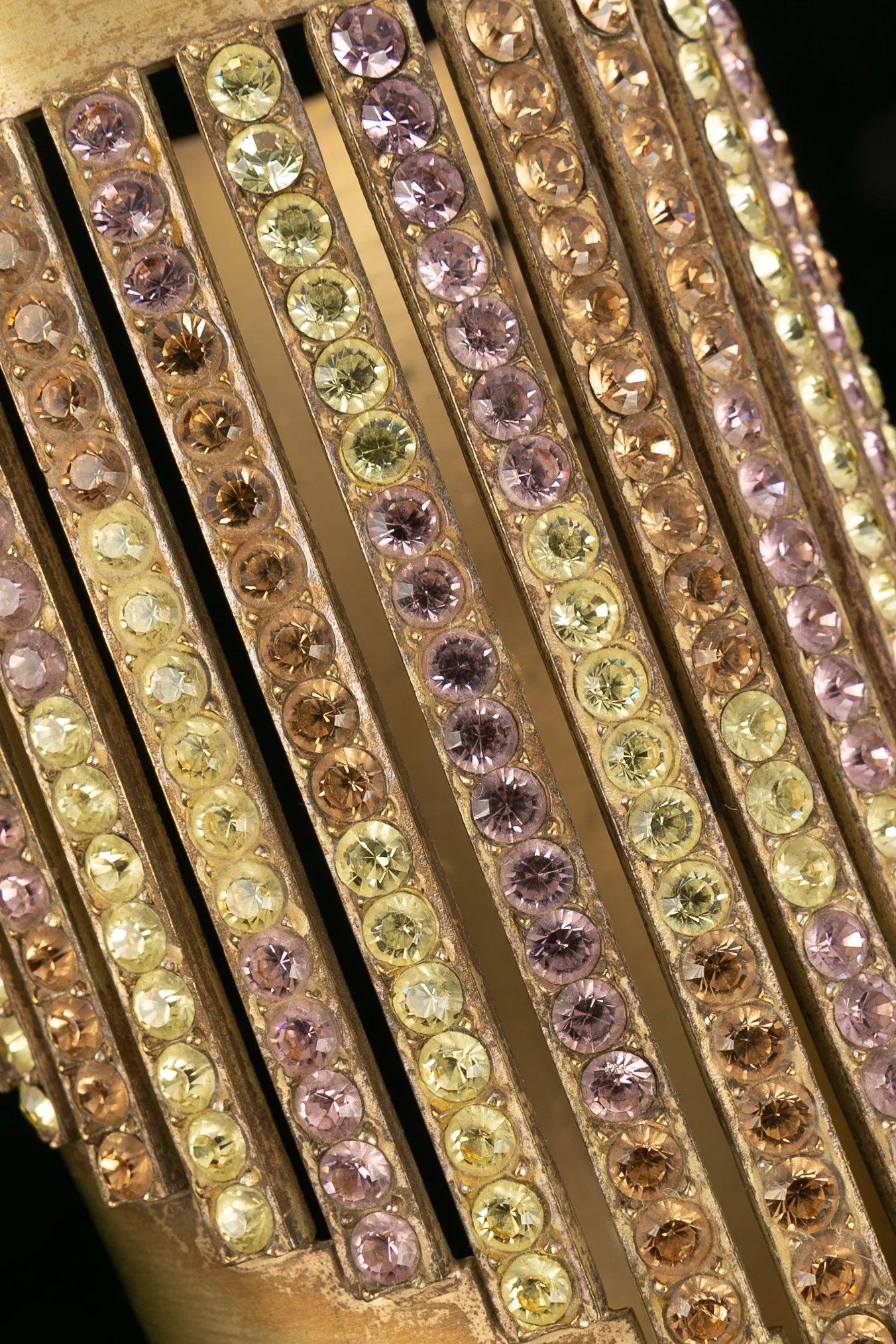 Chanel -Golden metal sleeve paved with multicolored rhinestones.

Additional information:
Dimensions: Maximum circumference: 24 cm 
Minimum circumference: 21 cm 
Height: 12 cm 
Opening: 3.5 cm
Condition: Good condition
Seller Ref number: BRAB14