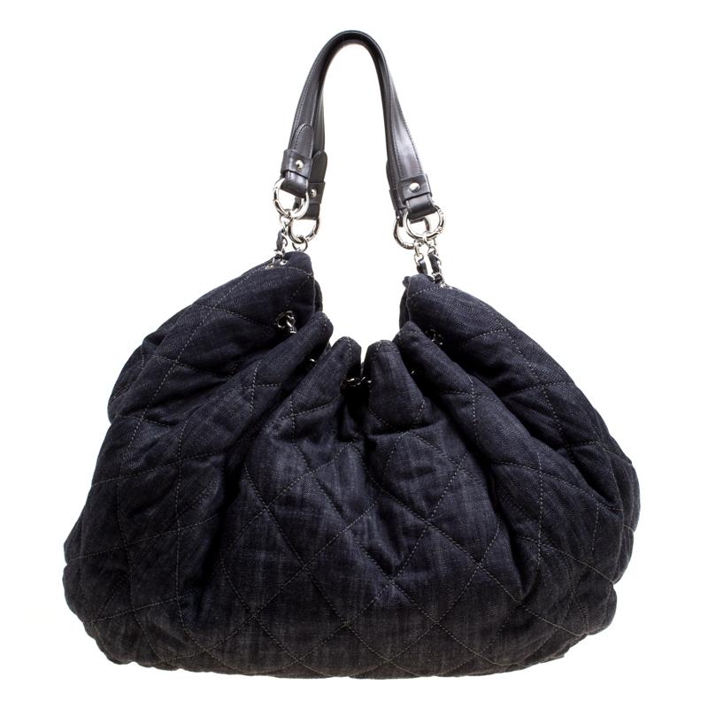 Chanel's bucket bag will add a stylish element to your wardrobe. Crafted with dark blue denim fabric, it carries the signature quilted pattern all over and has a soft structure with dual top handles attached with chain-links and rings. The top has a
