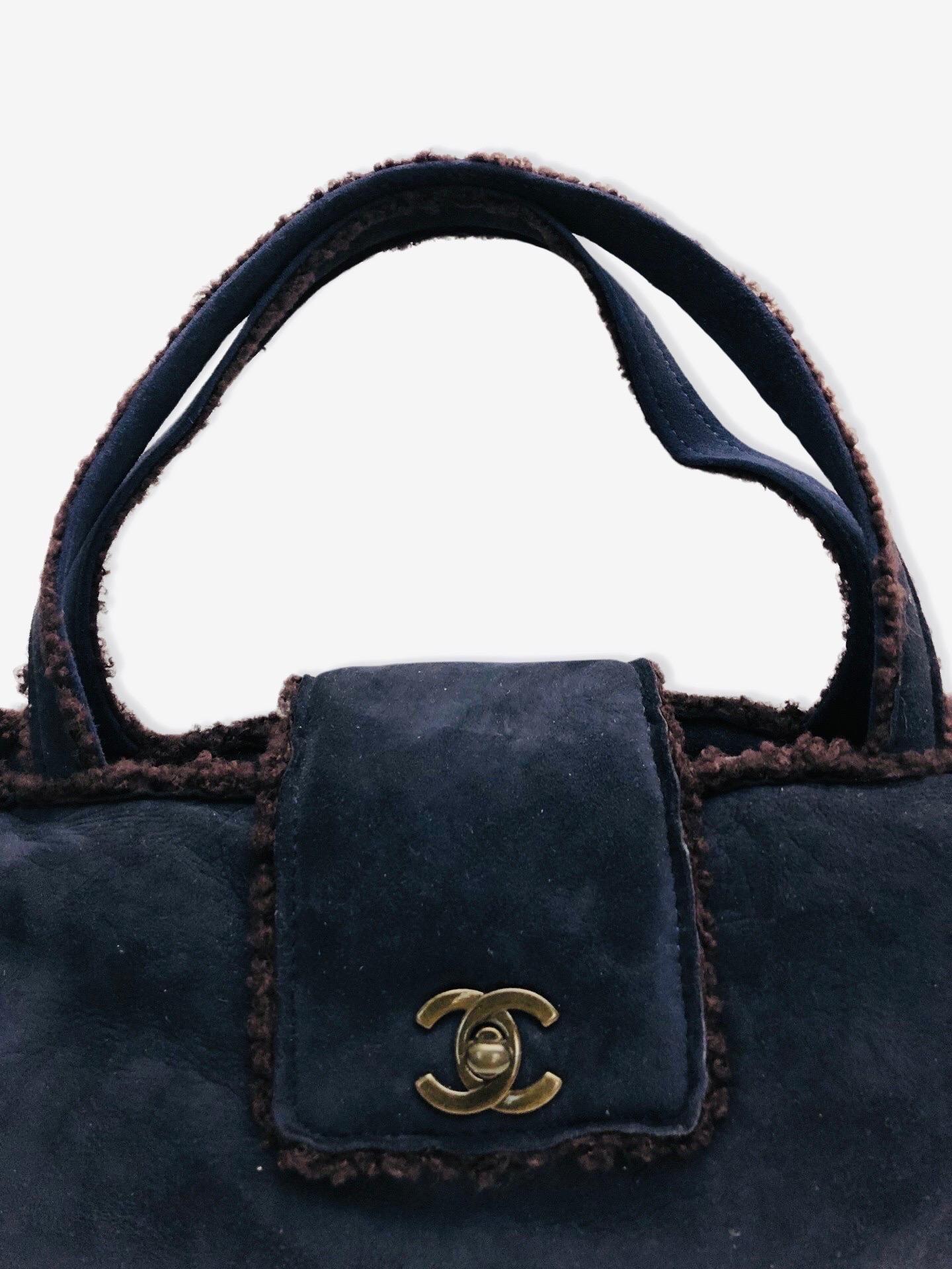 - Chanel dark blue suede shoulder shoulder handbag from 1998 collection. 

- Featuring brown shearling mouton trim overall. 

- CC turnlock flap closure. 

- Interior zip pocket. 

- Length: 32cm. Height: 16cm. Width: 7.5cm. Handle Drop: 18cm