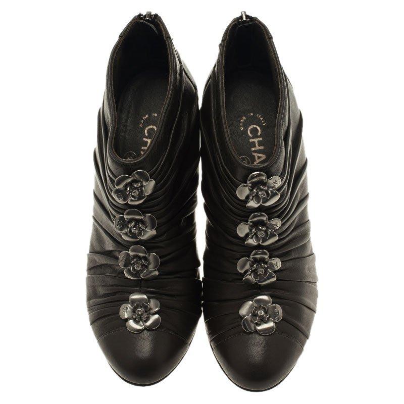 These Chanel ankle boots are simply stunning. They are crafted from dark grey leather and feature almond toes with 'CC' embossed camellia flower detailing on the pleated exterior. They come with back zip closures and are accented with 11 cm