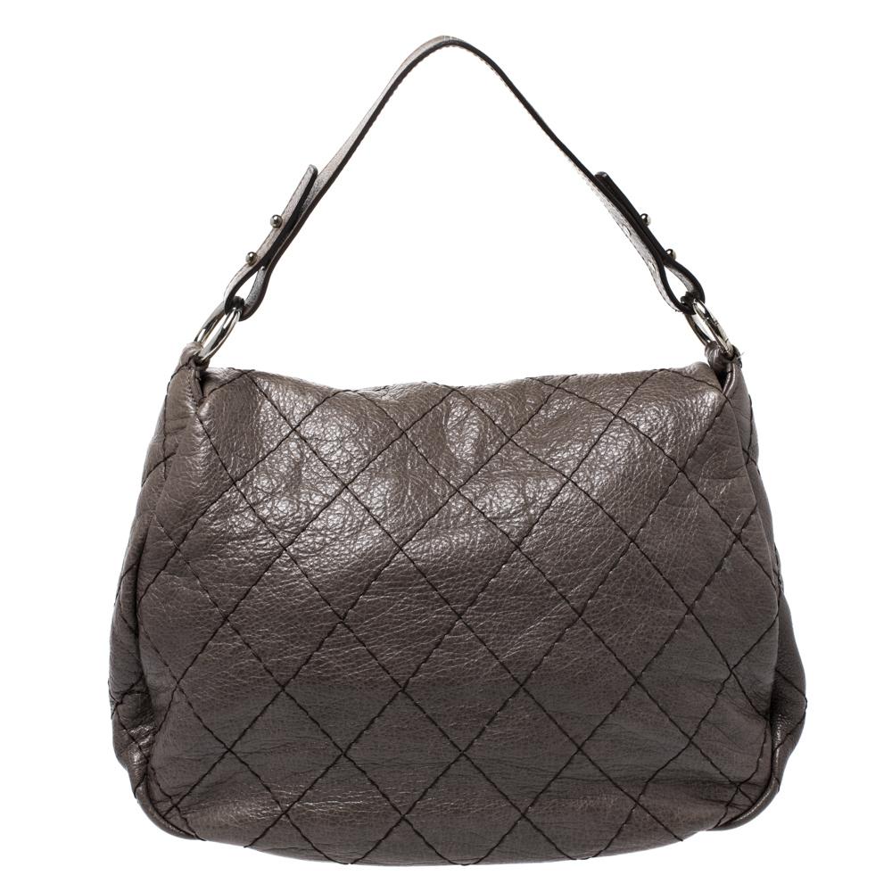 Unmistakably designed in Italy from Chanel’s signature quilted leather in dark grey, this On the Road flap bag presents a chic touch to one’s evening silhouette. Adorned with a flat shoulder strap, the outer flap is secured with a turn-lock closure