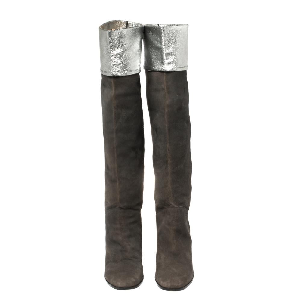 Chanel never fails to design classic styles that become favorites in one's closet. These dark grey knee-length boots for women are a fine example. Made from suede, they feature covered toes, 9 cm high heels, and folded tops that reveal metallic