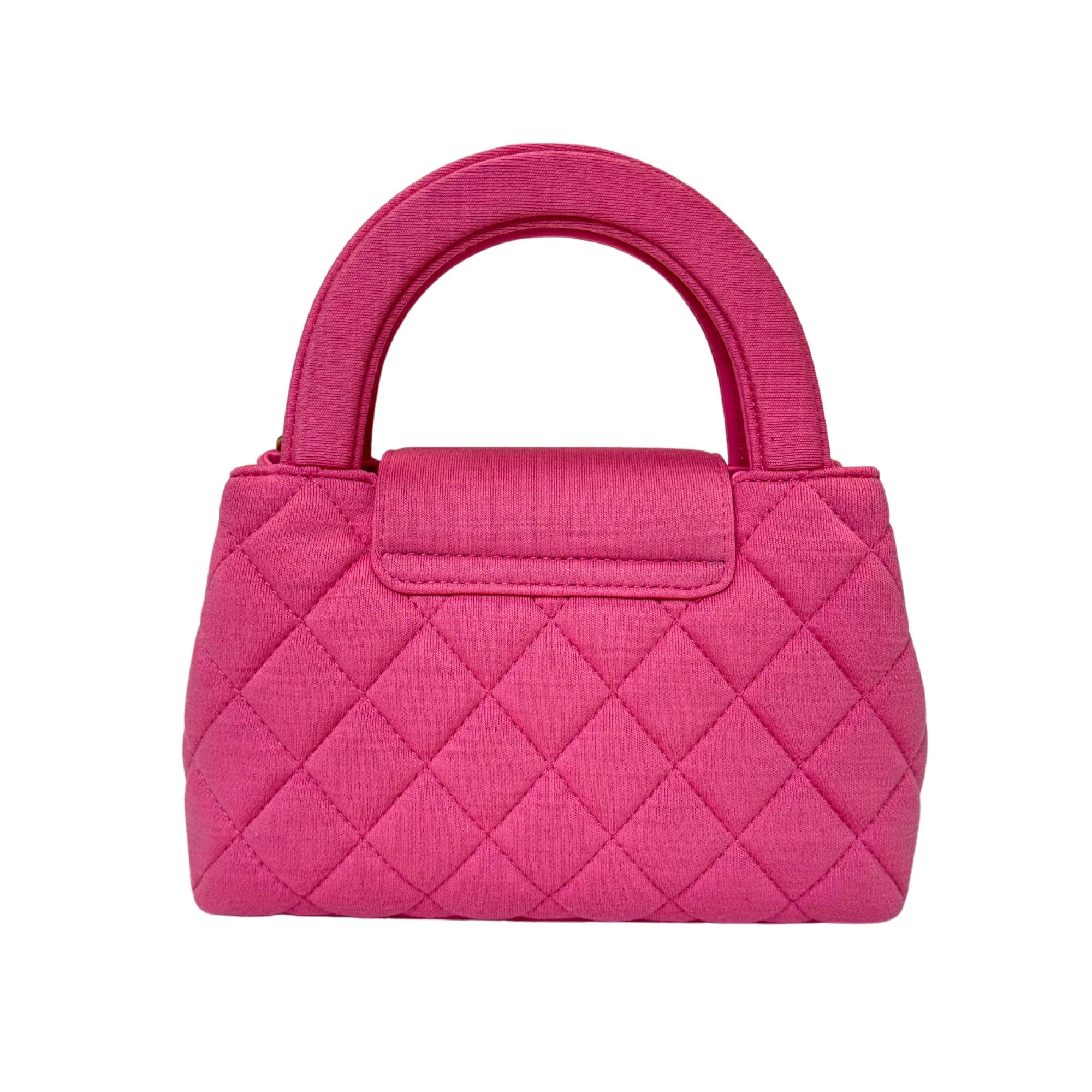 Introducing the Chanel Small Shopper Tote in dark pink, crafted from jersey fabric with a quilted stitch. Accentuated by aged gold hardware, including the signature CC turn-lock on the front flap, this bag exudes sophistication. Boasting dual top