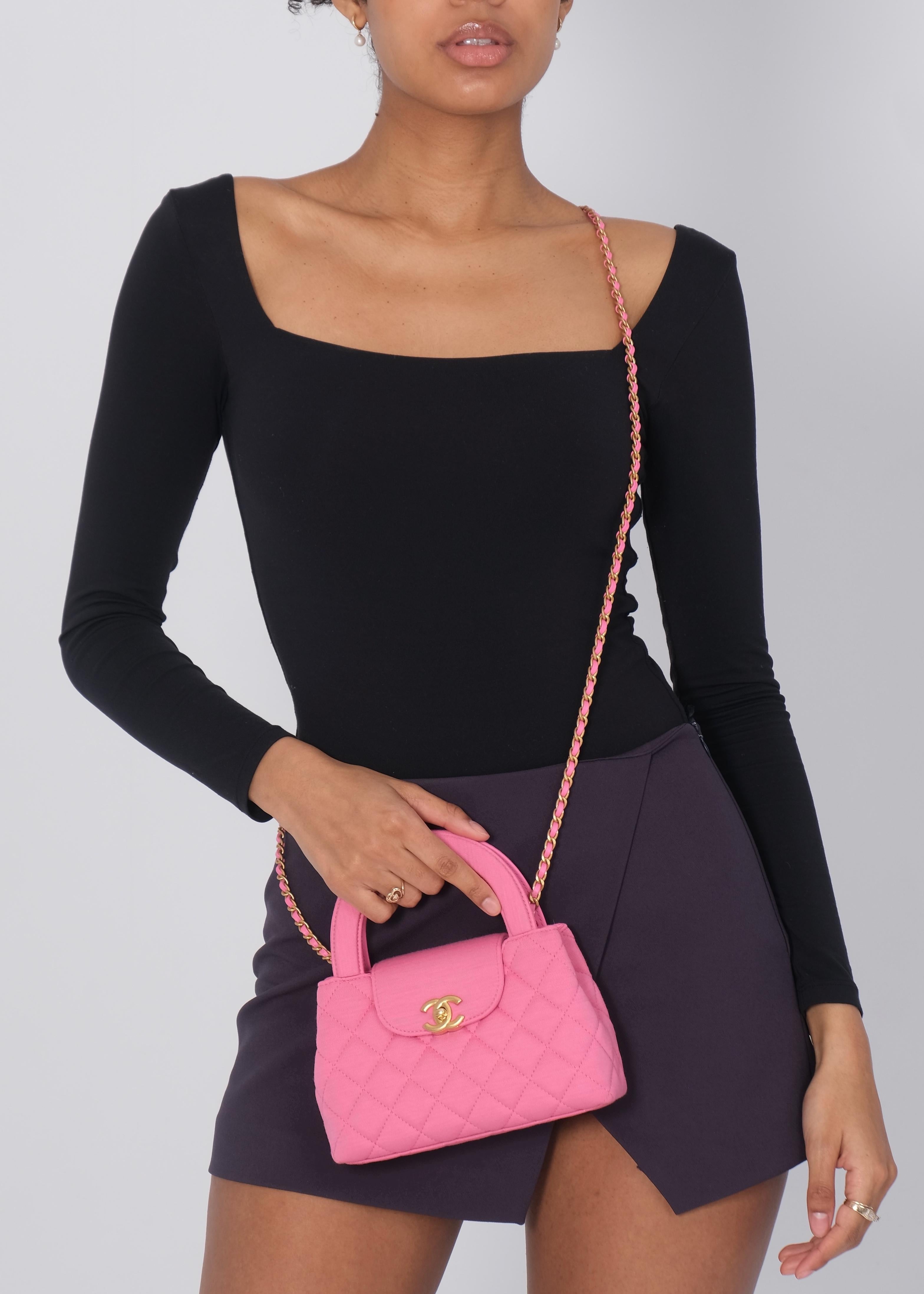 Introducing the Chanel Small Shopper Tote in dark pink size small. The bag is made from jersey fabric with a quilted stitch. Accentuated by aged gold hardware, including the signature CC turn-lock on the front flap. The dual top handles and long