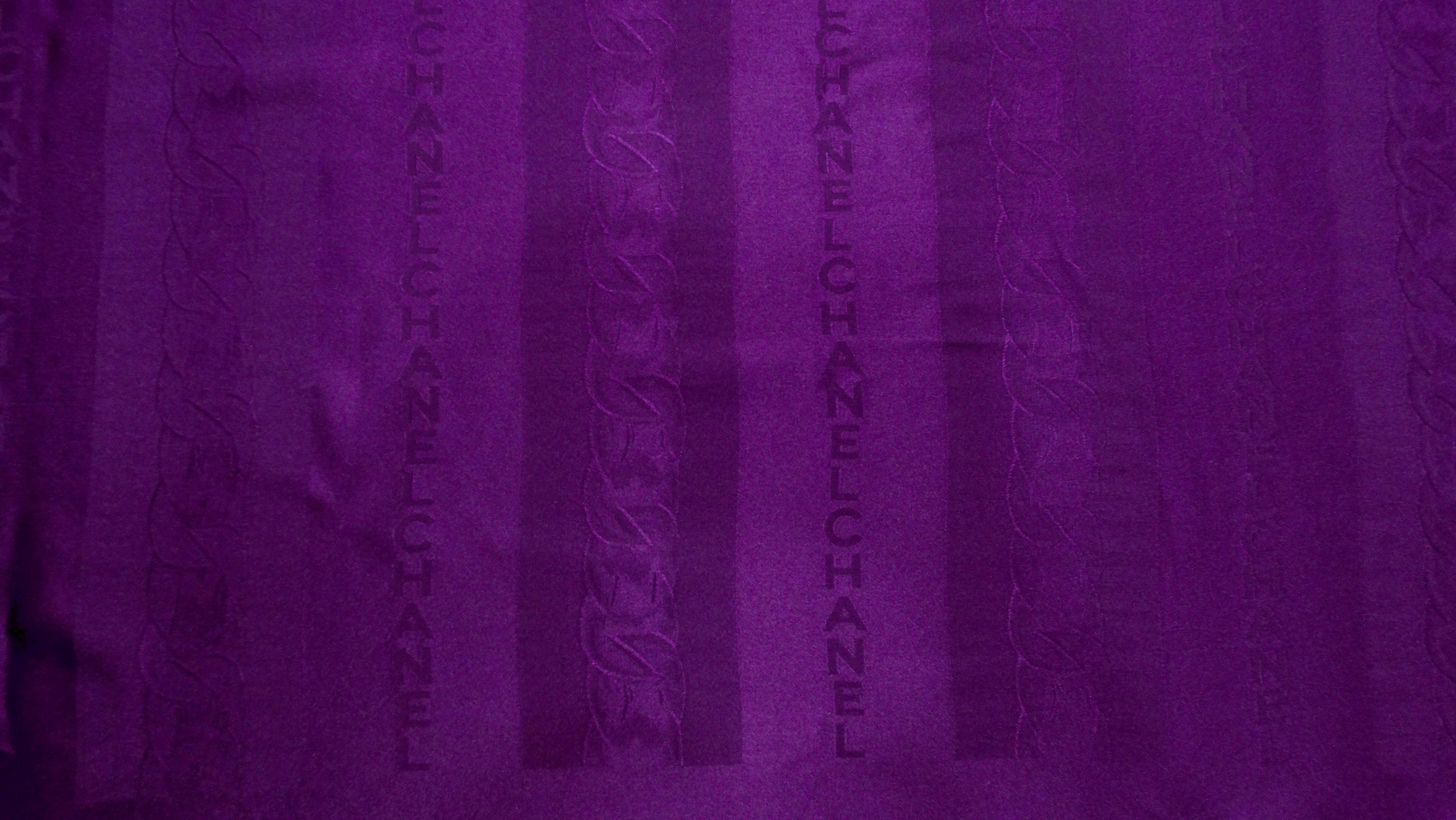 The Chanel Dark Purple Monogram Logo Print Silk Scarf from the circa 1980s epitomizes timeless elegance and sophisticated style. Crafted from luxurious silk, it features the iconic Chanel words and chain print pattern in a rich dark purple hue,