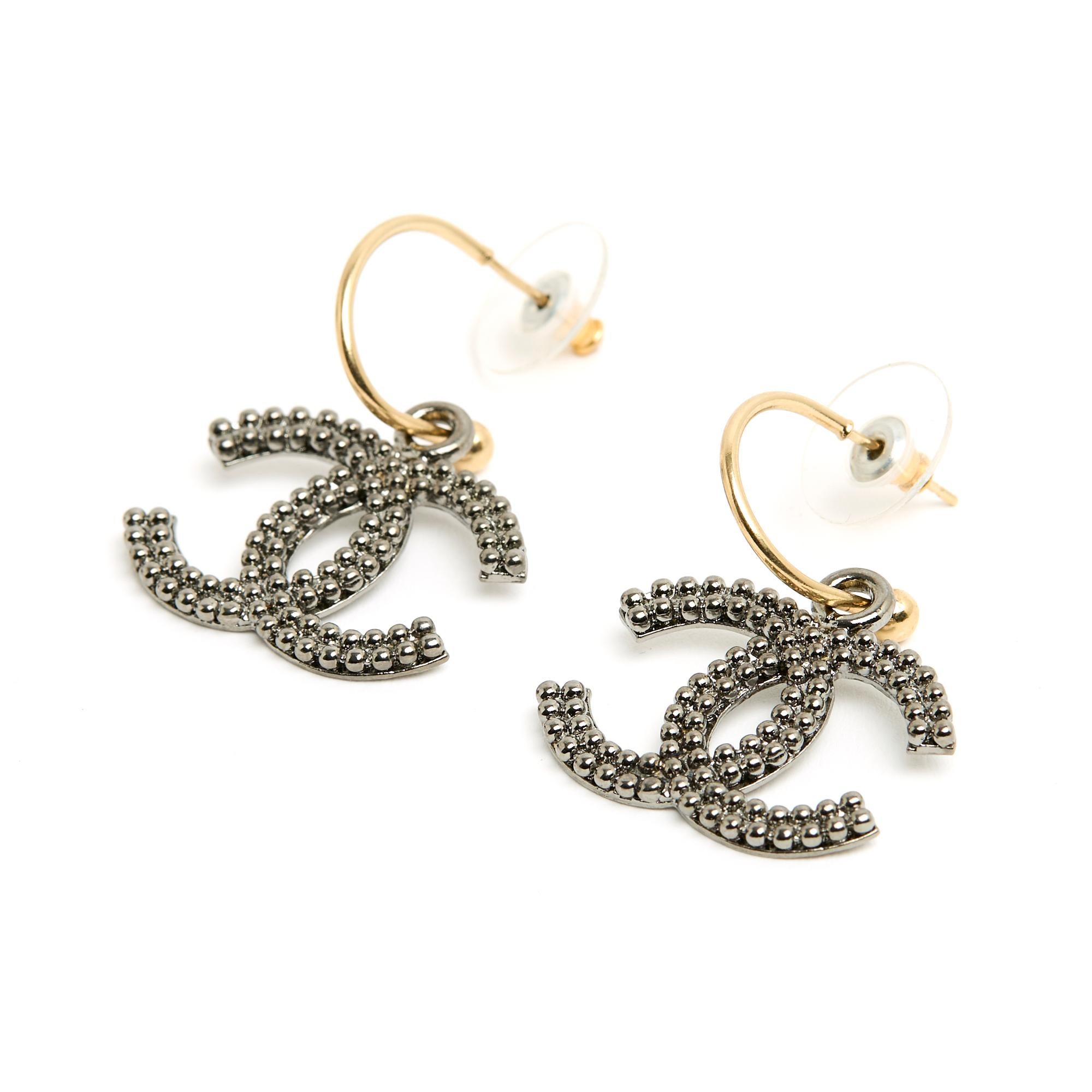 Chanel-Ohrringe, bestehend aus einem kleinen Reif aus goldenem Metall und einem Anhänger in Form des Chanel CC-Logos aus geschwärztem, silbernem Metall, genannt 