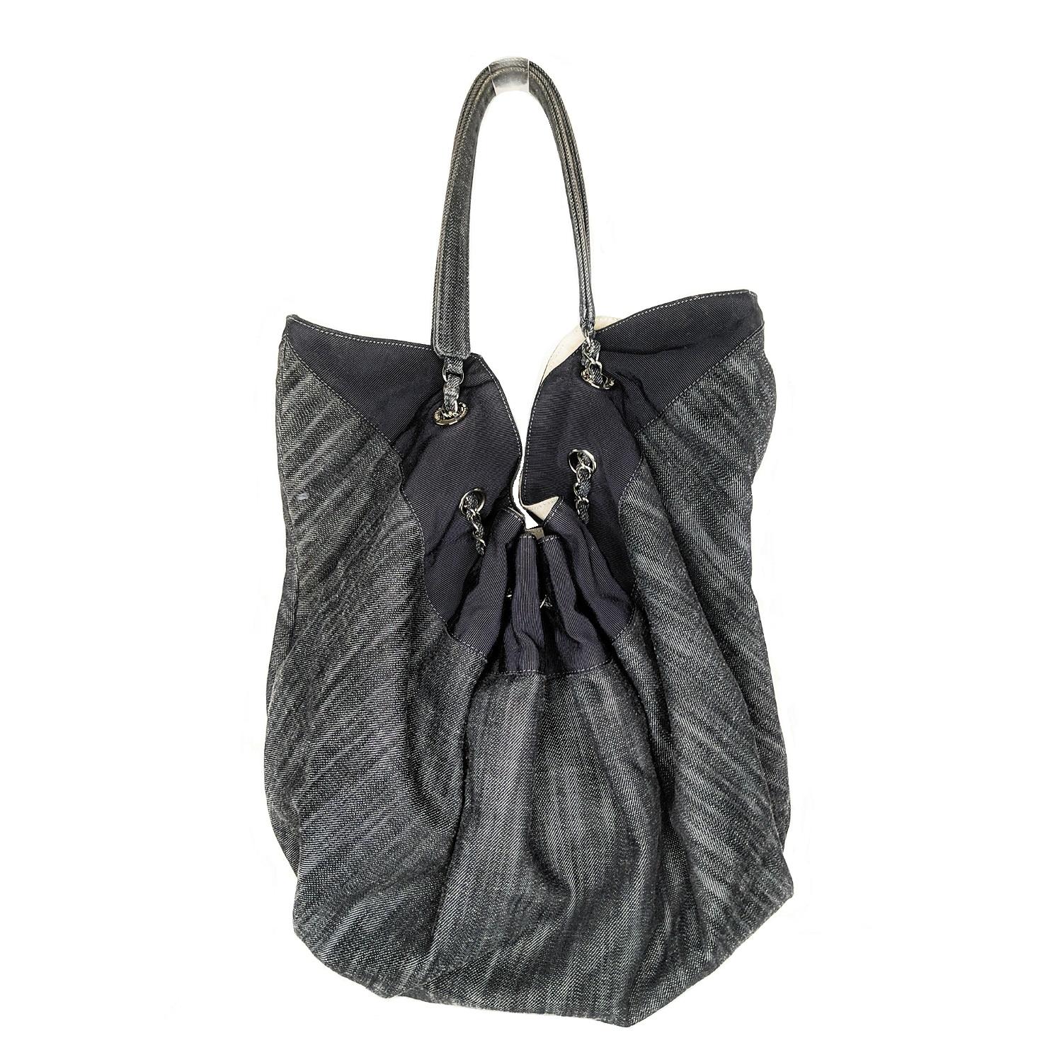 The Chanel Blue Denim Stretch Spirit Tote Bag features durable blue denim with a large embroidered CC logo and elastic around the opening of the bag, along with unique denim and chain straps. Estimated retail $2,750.

Designer: Chanel
Material: Dark
