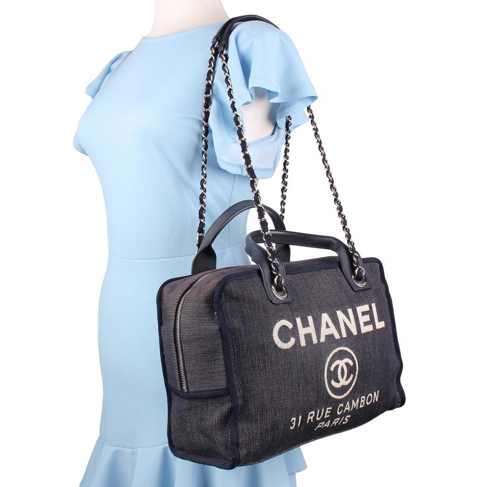 Authentic, pre-owned Chanel Deauville shoulder bag tote in Blue. Features blue canvas, silver-tone hardware, dual shoulder straps with chain-link and blue trim, white embroidered logo embellishment at front face, tonal canvas lining, and two pockets