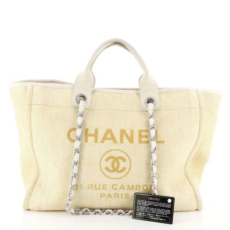 This Chanel Deauville Tote Canvas Large, crafted in yellow canvas, this stylish, features dual-flat handles, woven-in chain link straps, embroidered CC logo with Chanel's famous parisian store address and silver-tone hardware. Its magnetic snap