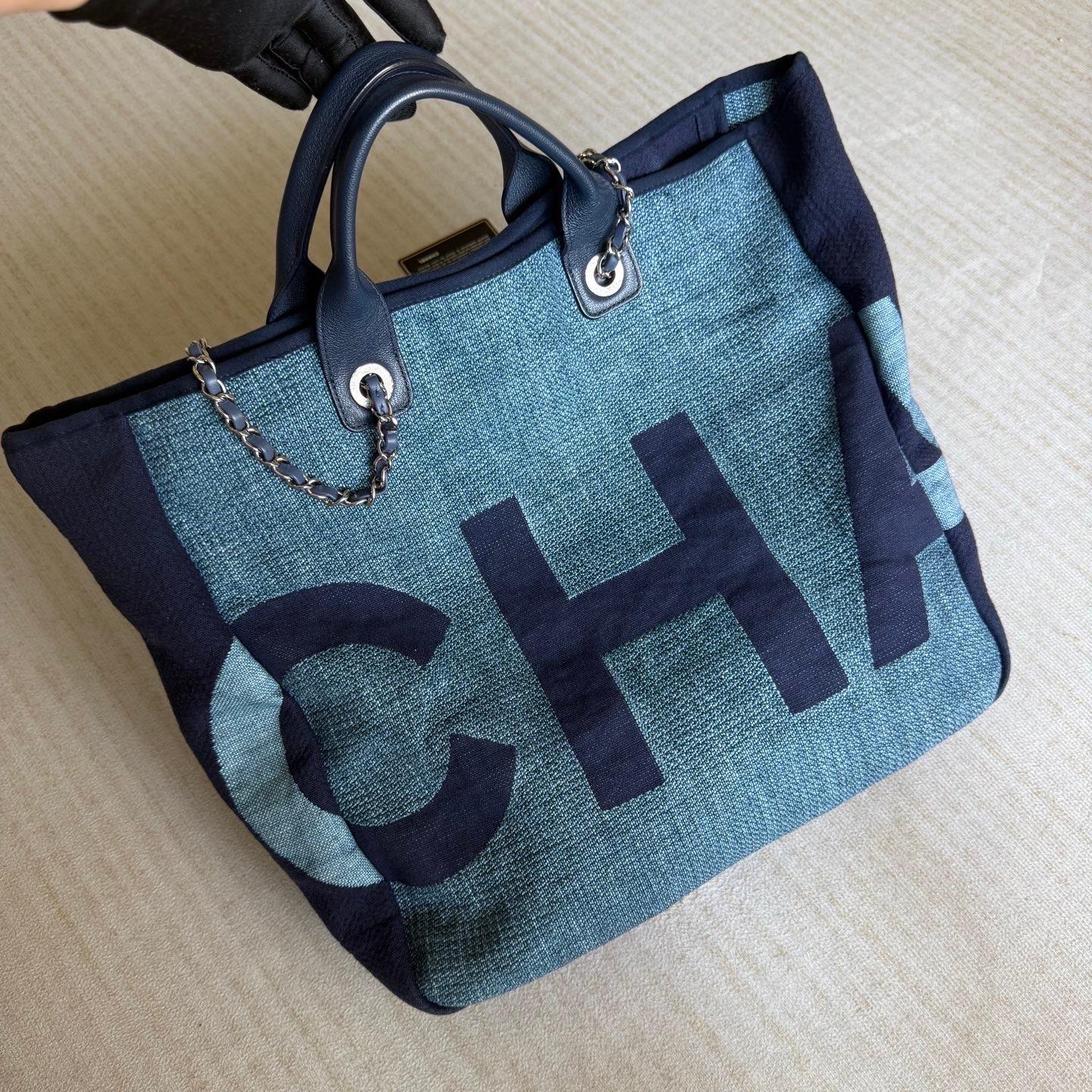 Le fourre-tout Chanel Deauville, du nom de la station balnéaire française, est un incontournable de l'été, alliant élégance et fonctionnalité. Confectionné dans une matière légère rappelant le denim, il se porte à la main ou à l'épaule grâce à sa