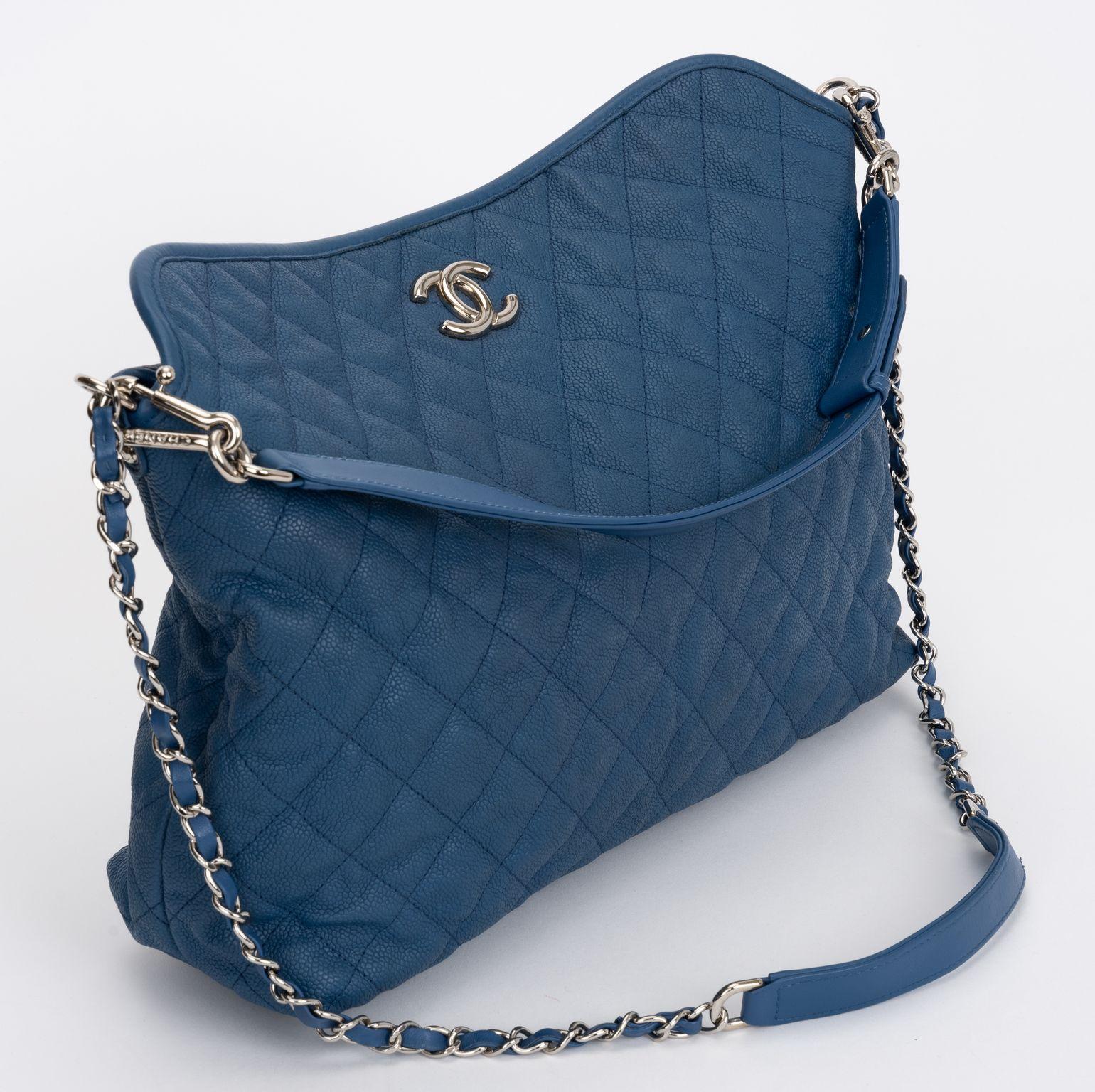 The Chanel Caviar Quilted Hobo in denim Blue leather features silver chain link shoulder strap threaded with leather and a removable shorter strap. Interior has a zipper pocket and a patch pocket. 
Short strap drop 6.5, long shoulder drop 16