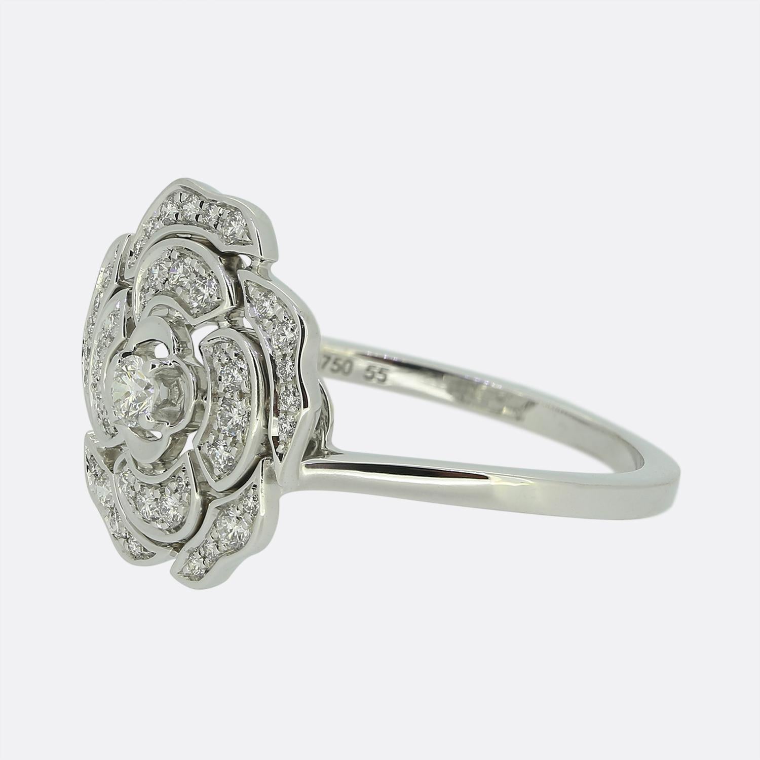 Hier haben wir einen wunderschönen Clusterring mit einem bezaubernden floralen Design, der von Chanel sorgfältig gefertigt wurde. Das Herzstück des Schmuckstücks ist ein einzelner runder Diamant im Brillantschliff, der elegant gefasst ist und die
