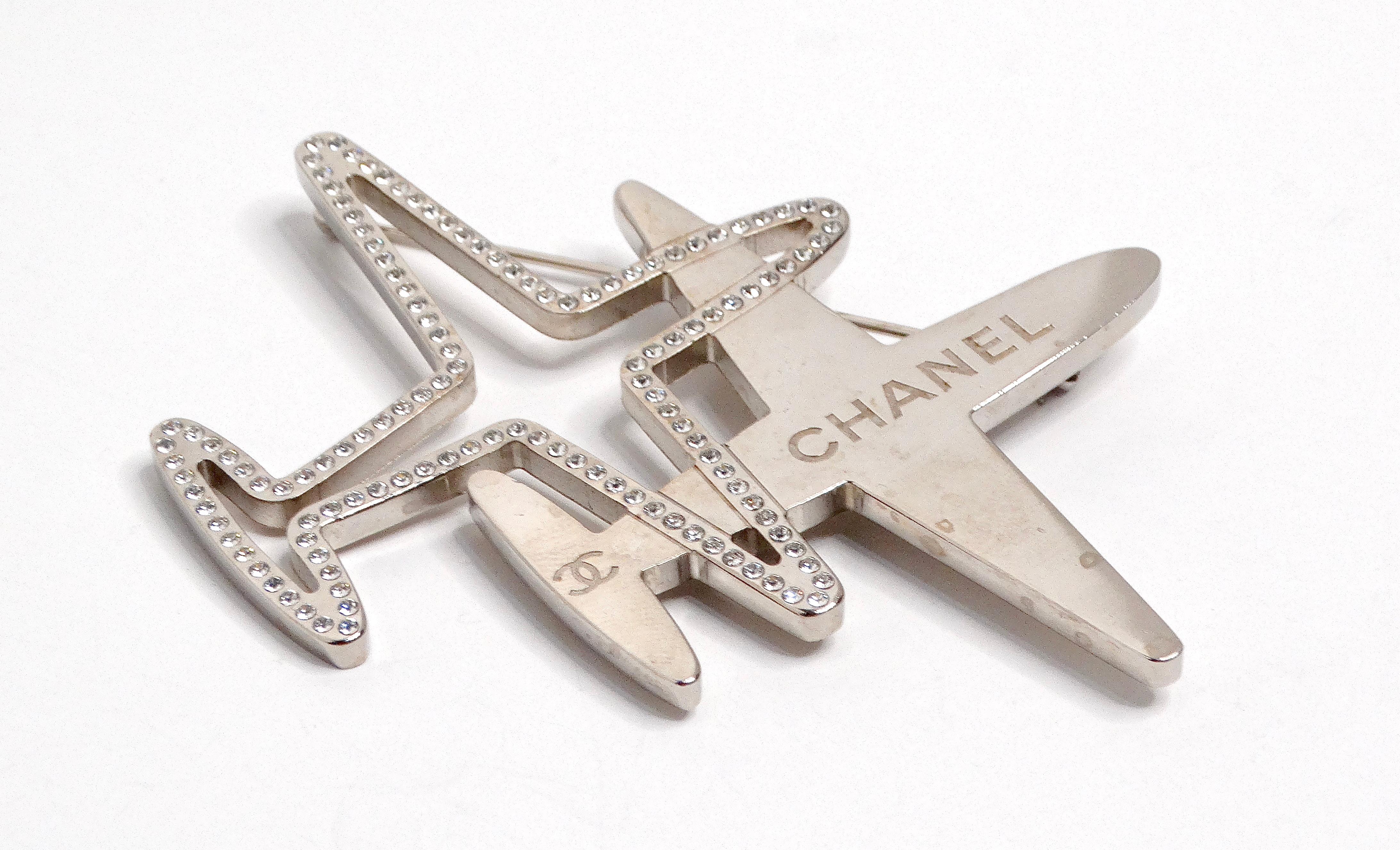 Die Chanel 2016 Double Airplane Crystal Silver-Tone Brooch ist ein echtes Statement-Stück, das die Essenz der High-Fashion-Laune verkörpert. Diese Brosche mit zwei sich überlappenden Flugzeugmotiven verkörpert Eleganz und Verspieltheit. Die erste