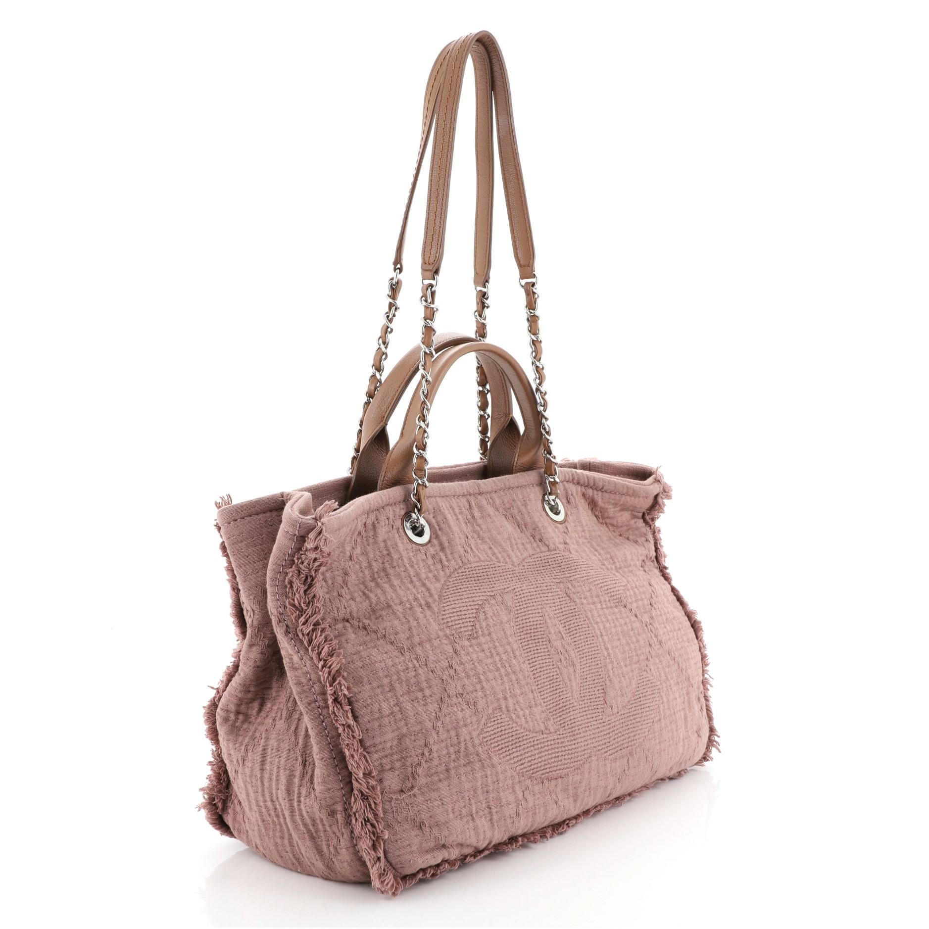 This Chanel Double Face Deauville Tote Fringe Quilted Canvas Medium, crafted in pink quilted canvas, features dual woven-in leather chain straps, dual top handles, CC logo at the front, and silver-tone hardware. Its magnetic snap closure opens to a