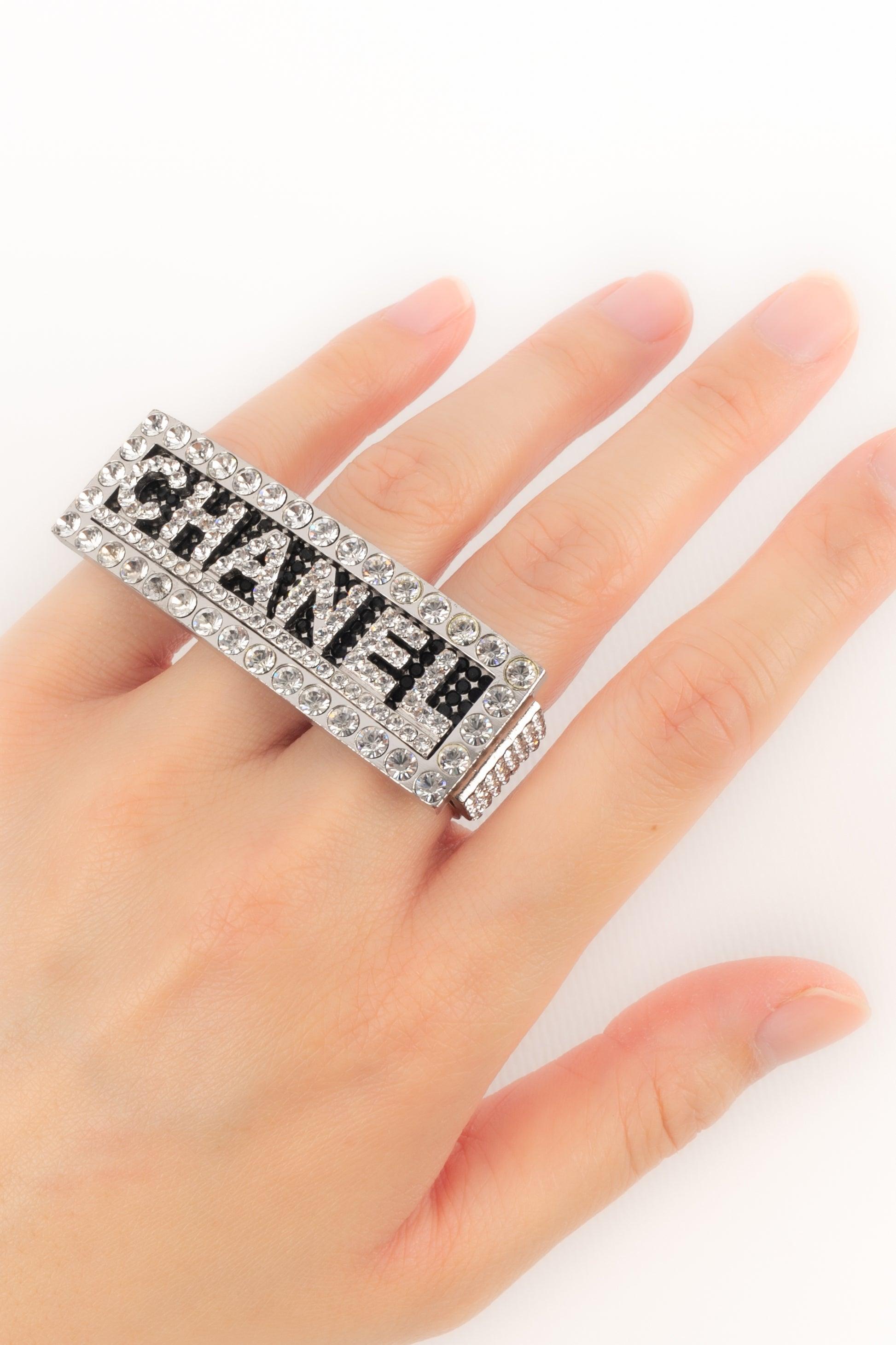 CHANEL - (Made in France) Silberner, mit Strasssteinen besetzter Metallring. Collection'S Frühling-Sommer 2002.

Zusätzliche Informationen:
Zustand: Sehr guter Zustand
Abmessungen: Verzierung: 6 cm x 2 cm

SKU:BGB6
