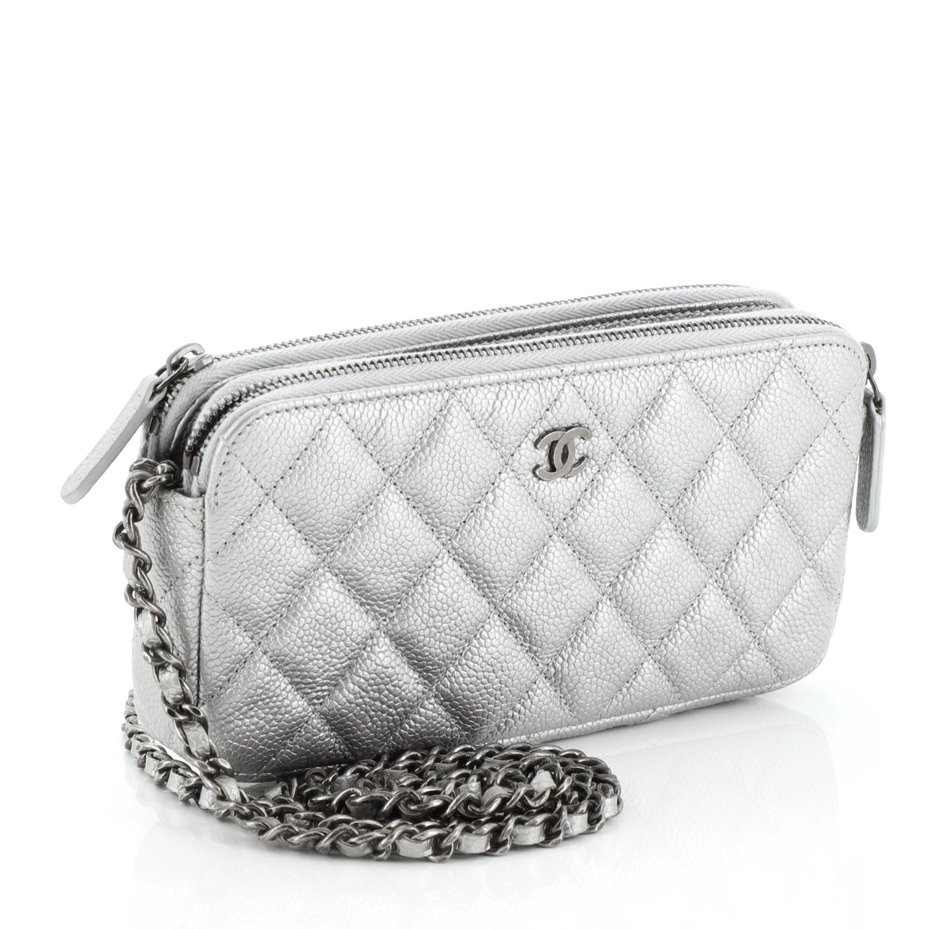 This Chanel Double Zip Clutch with Chain Quilted Caviar, crafted in gray quilted caviar leather, features a detachable woven-in leather chain strap, front CC logo and aged silver-tone hardware. Its double zip closures and an open center compartment