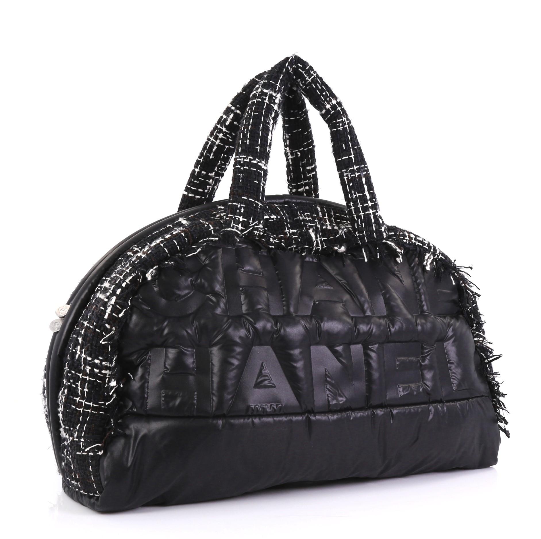 This Chanel Doudoune Bowling Bag Embossed Nylon with Tweed Large, crafted in black embossed nylon with tweed, features dual tweed handles, embossed Chanel logo and silver-tone hardware. Its zip closure opens to a black nylon interior with zip