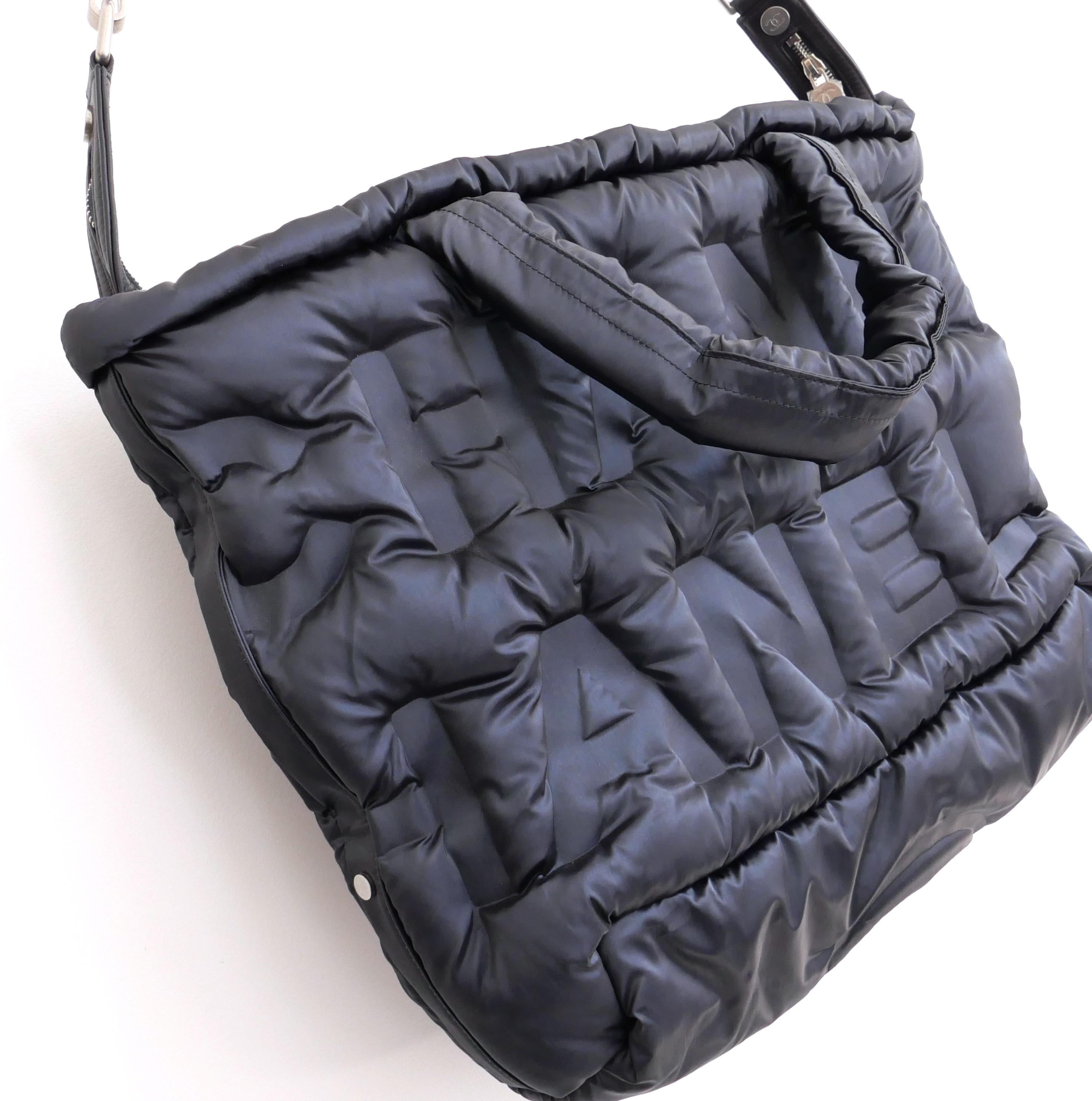 Fabulous Chanel Doudoune logo quilted nylon tote bag. Unworn with protective plastic cover on fobs. Made from glossy navy nylon with padded CHANEL logo throughout, it has chunky removable shoulder strap, padded handles and zip top with round CC