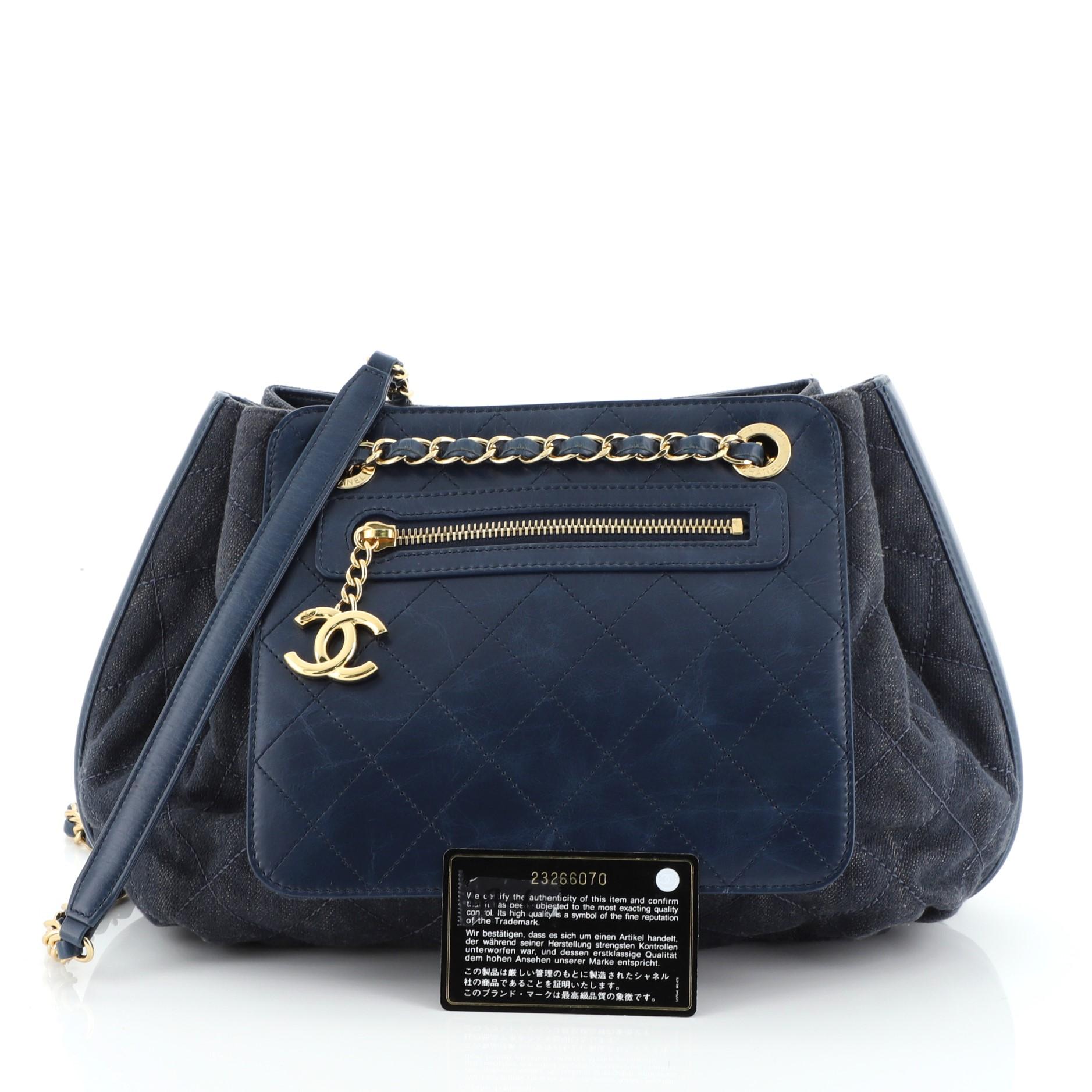 This Chanel Drawstring Shoulder Bag Quilted Denim and Aged Calfskin Medium, crafted from blue quilted denim and aged calfskin leather, features woven-in leather chain strap with leather shoulder pad, exterior front zip pocket, and gold-tone