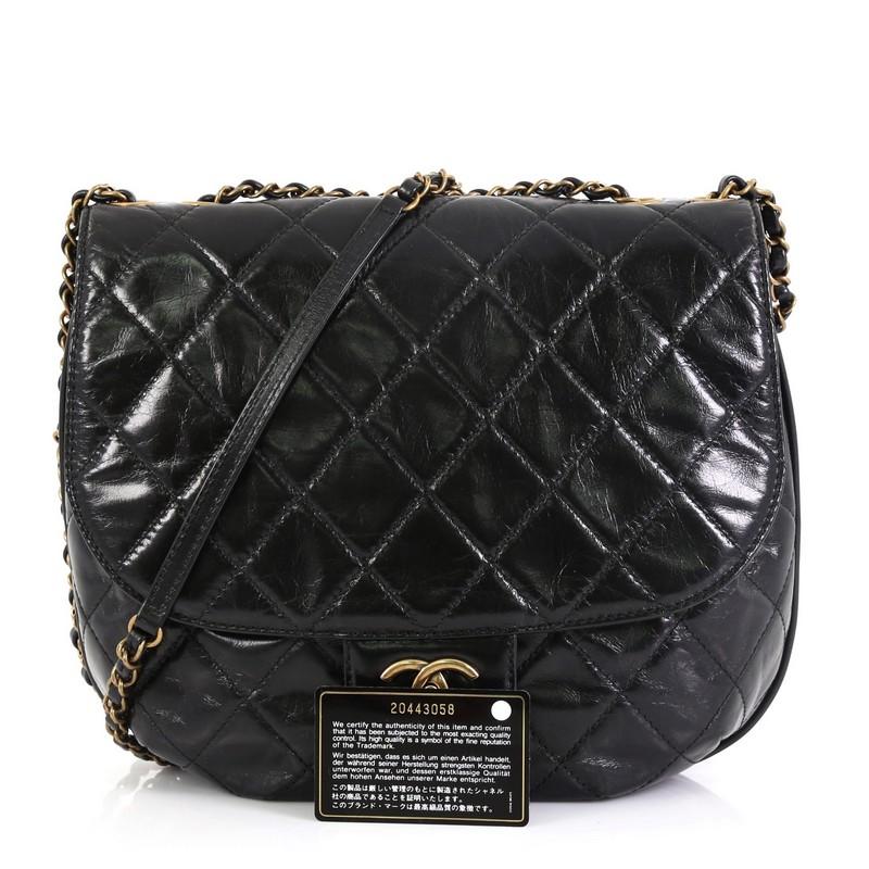 This Chanel Dubai Messenger Bag Quilted Aged Calfskin Medium, crafted from black quilted aged calfskin, features woven-in leather chain strap with leather pad, exterior back slip pocket, frontal flap, slip pocket under flap and aged gold-tone